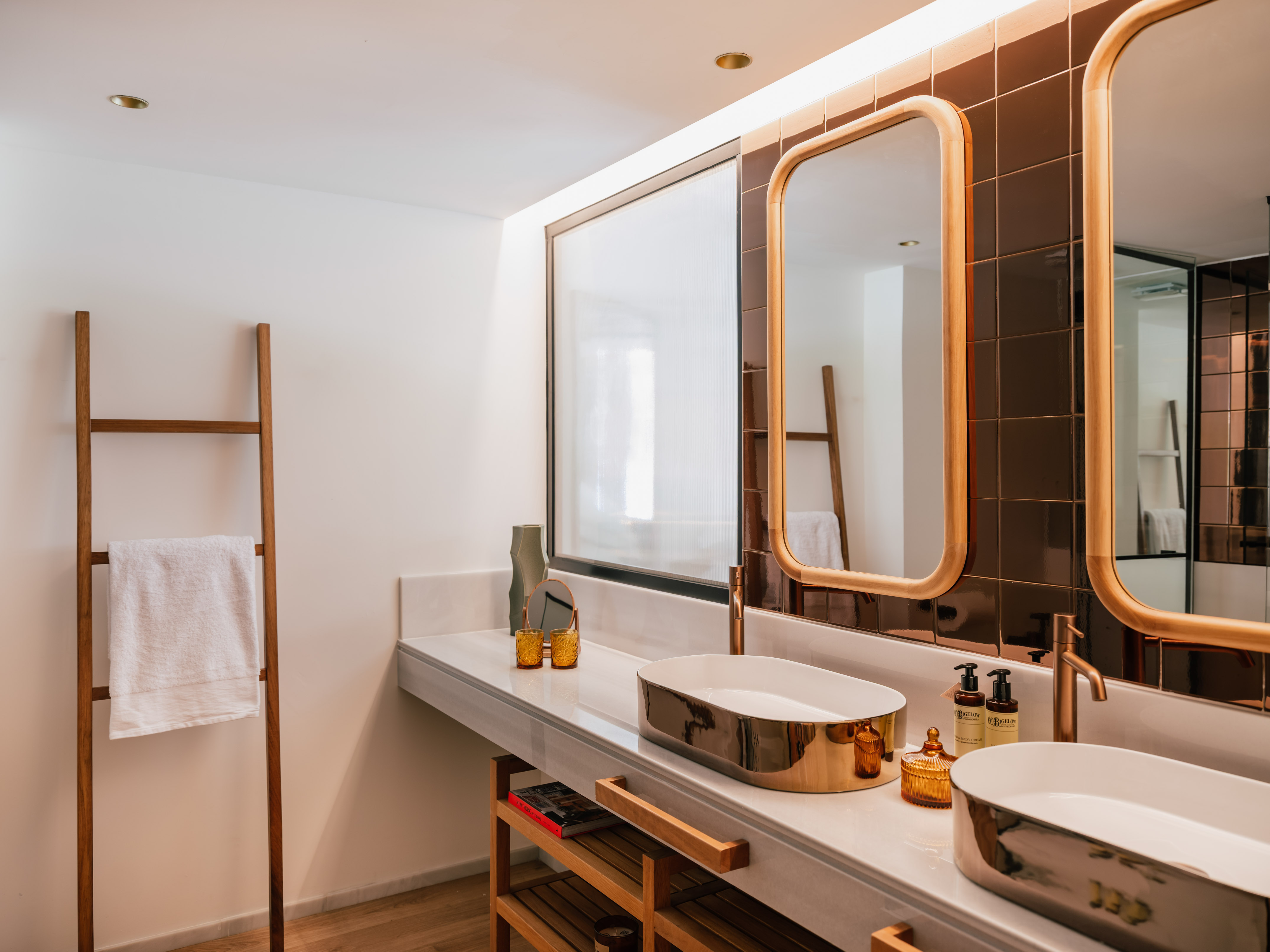 Modern bathroom with double gold sinks, marble counter, and wood framed mirrors.