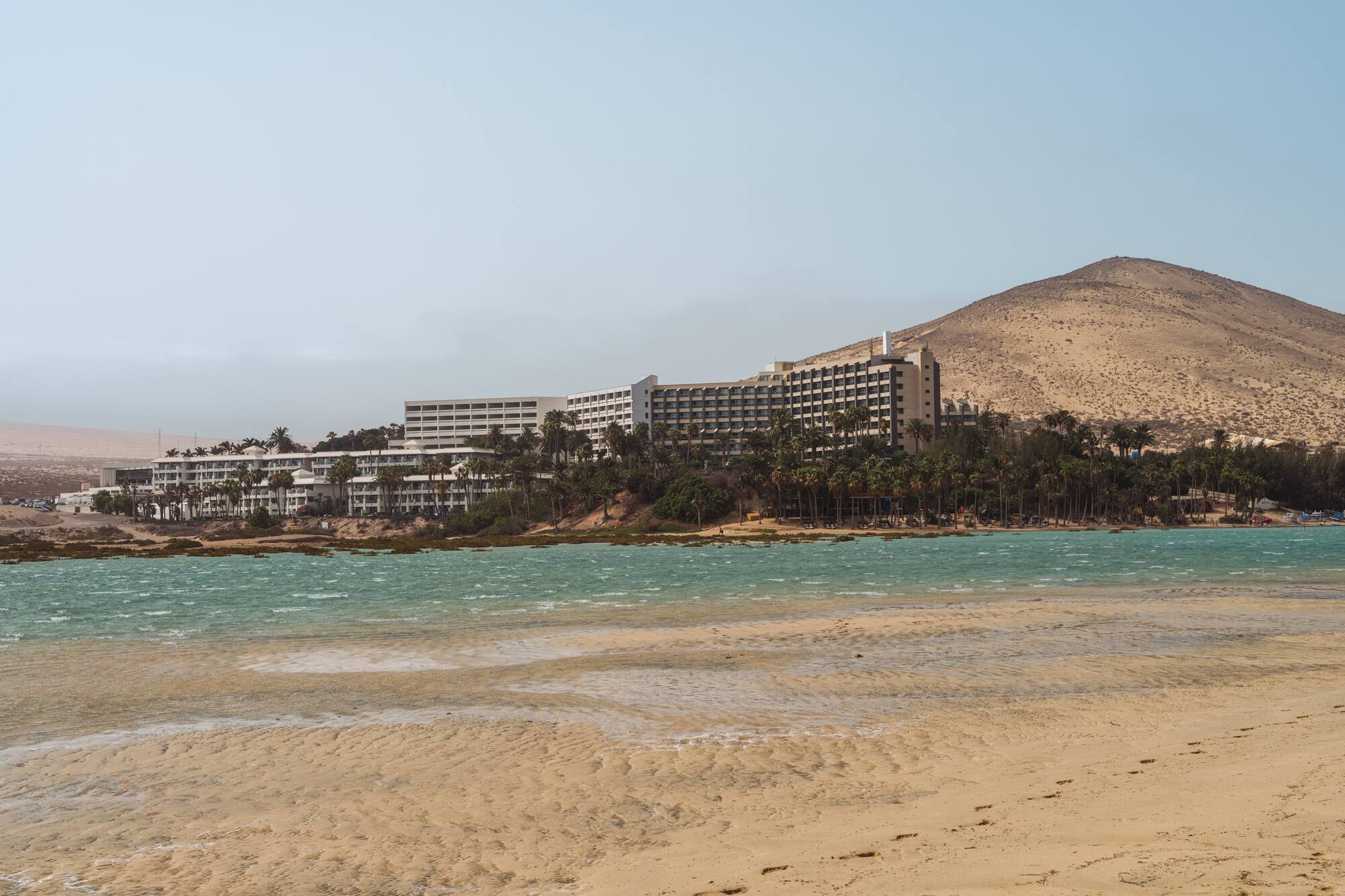 a beach with a building and mountains in the background