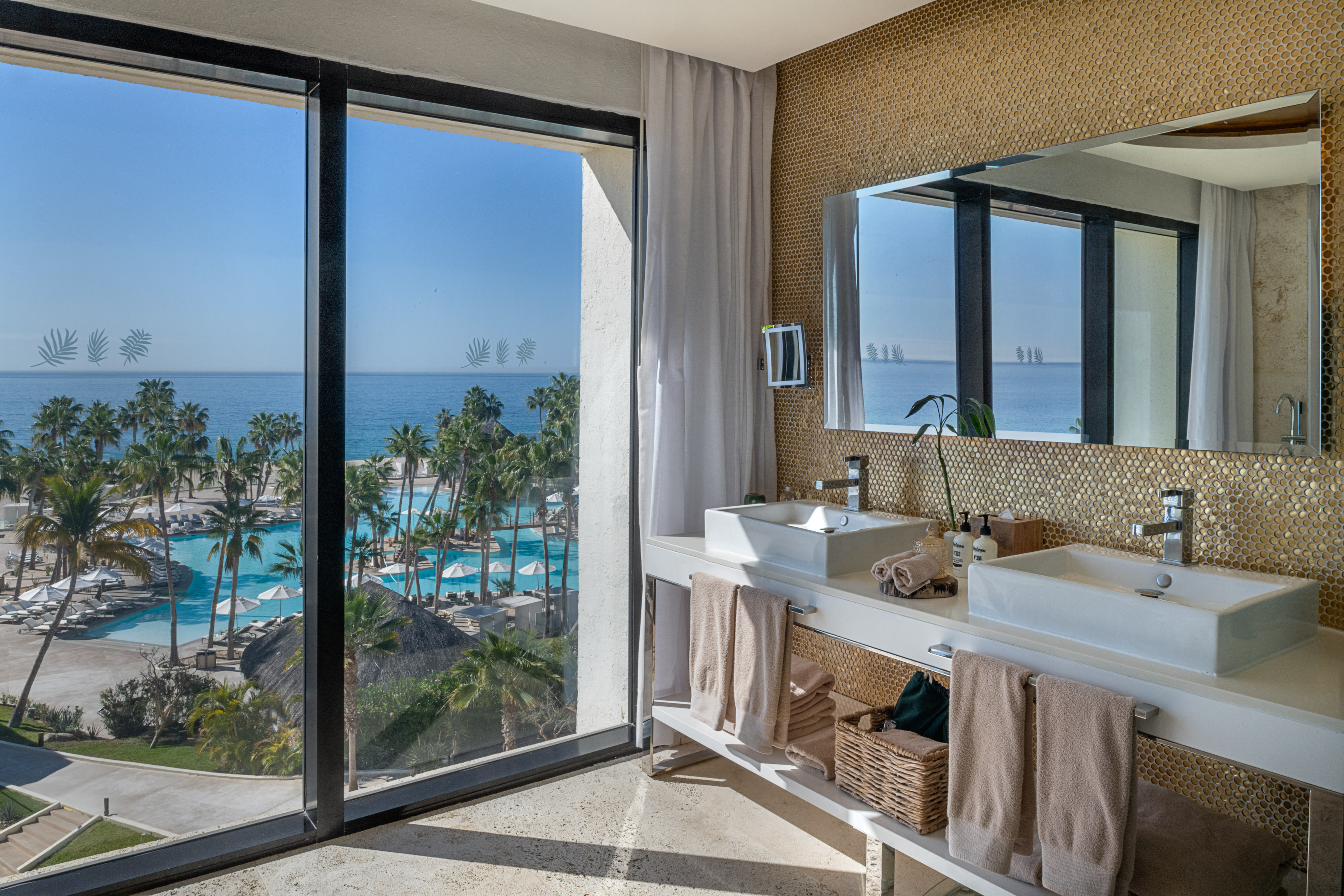 Ocean view bathroom with resort pool, palm trees, and modern double vanity.