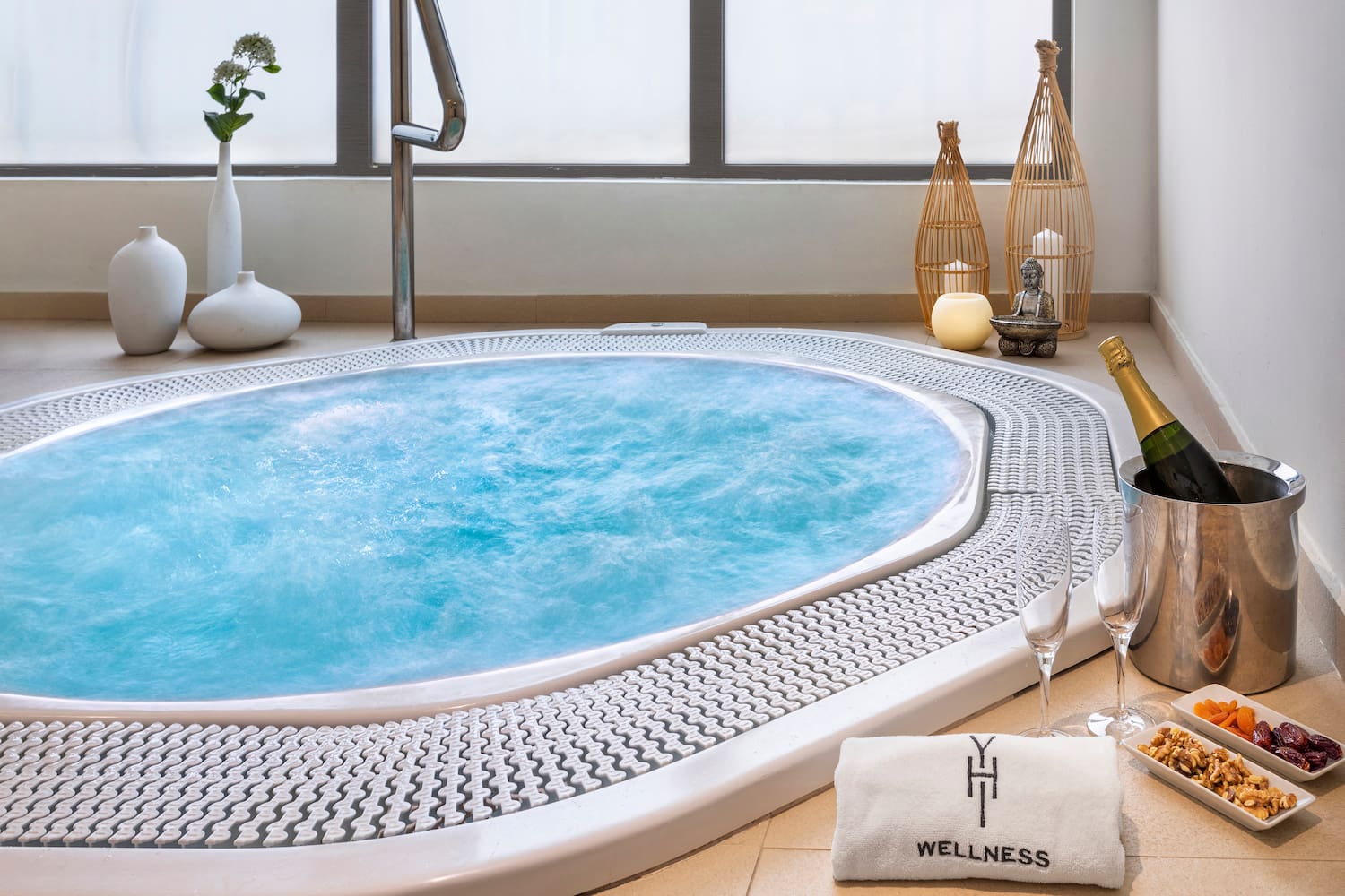 a hot tub with a towel and glasses of wine