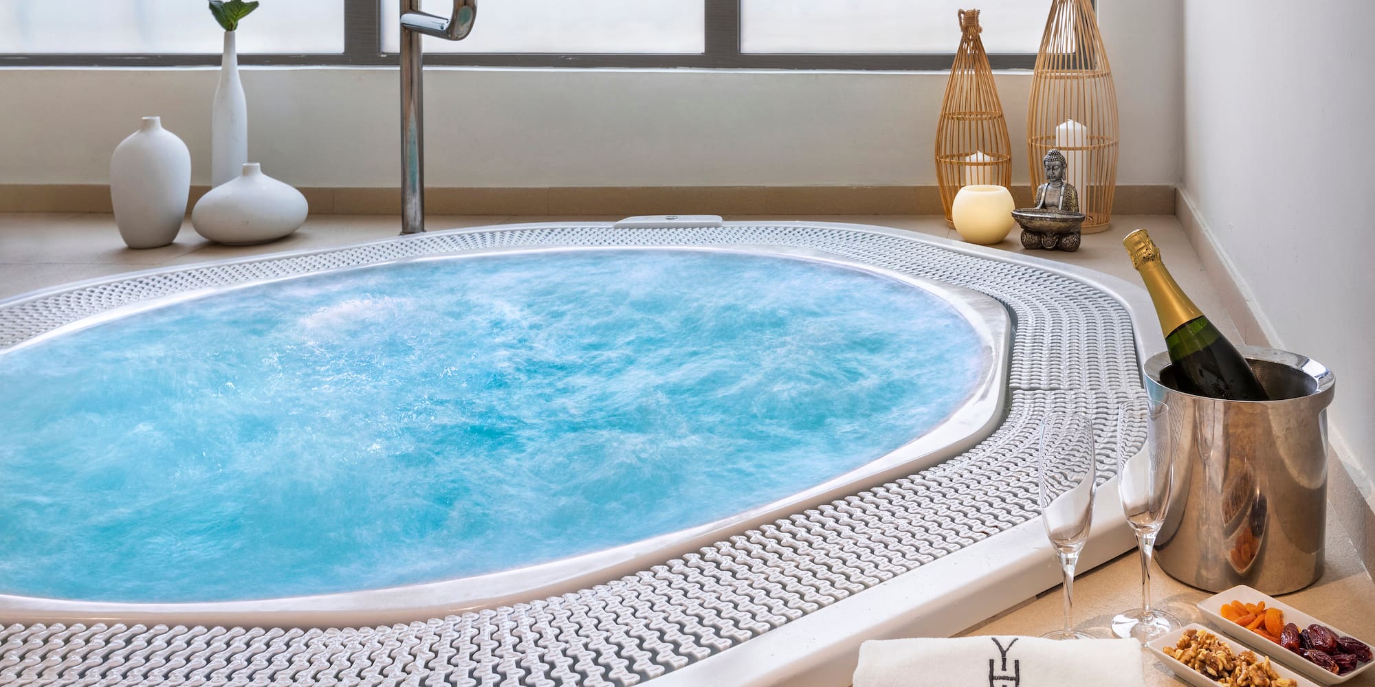 a hot tub with a towel and glasses of wine