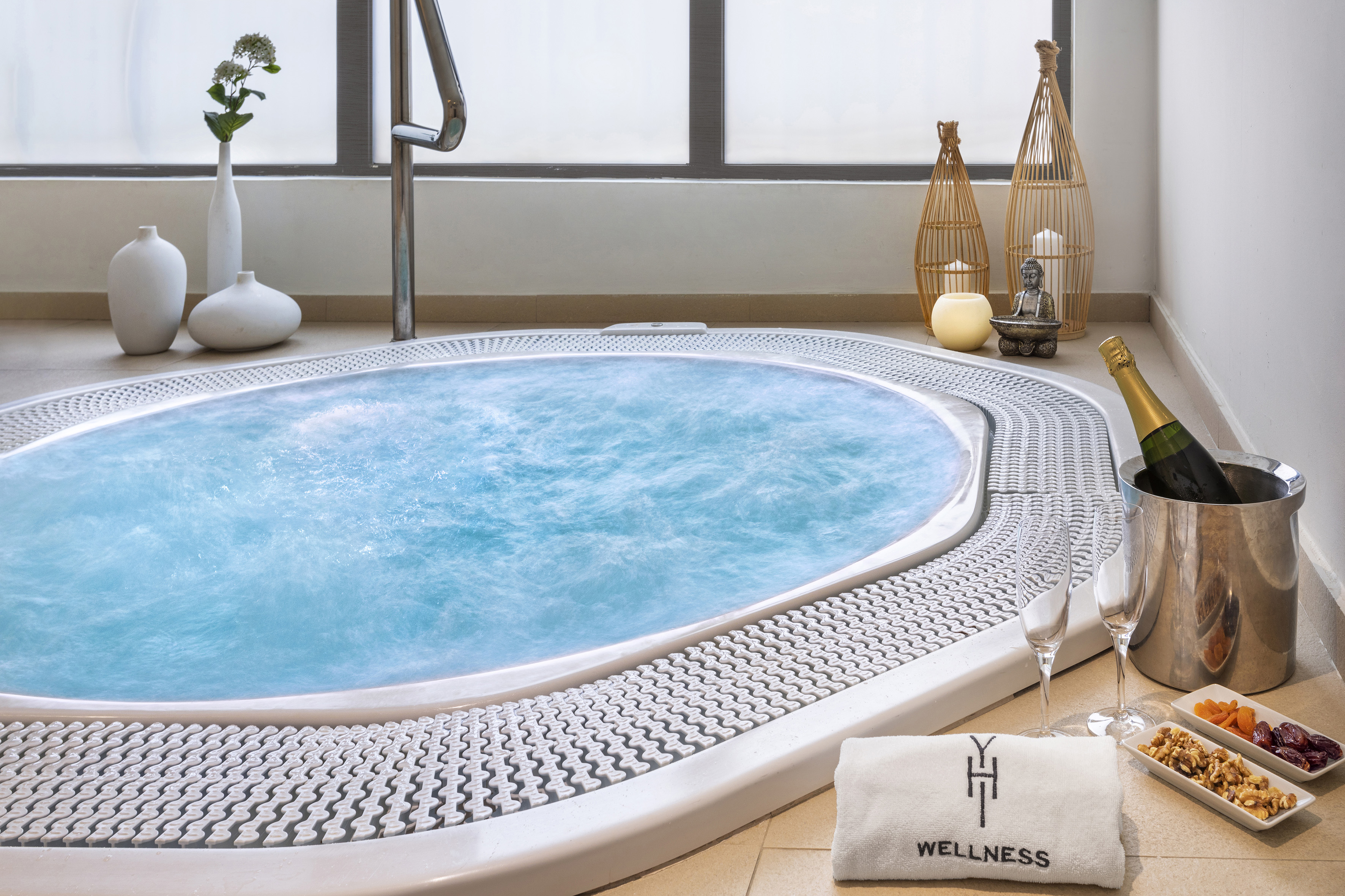 Bubbling spa jacuzzi with champagne, wellness towel, and relaxation snacks.