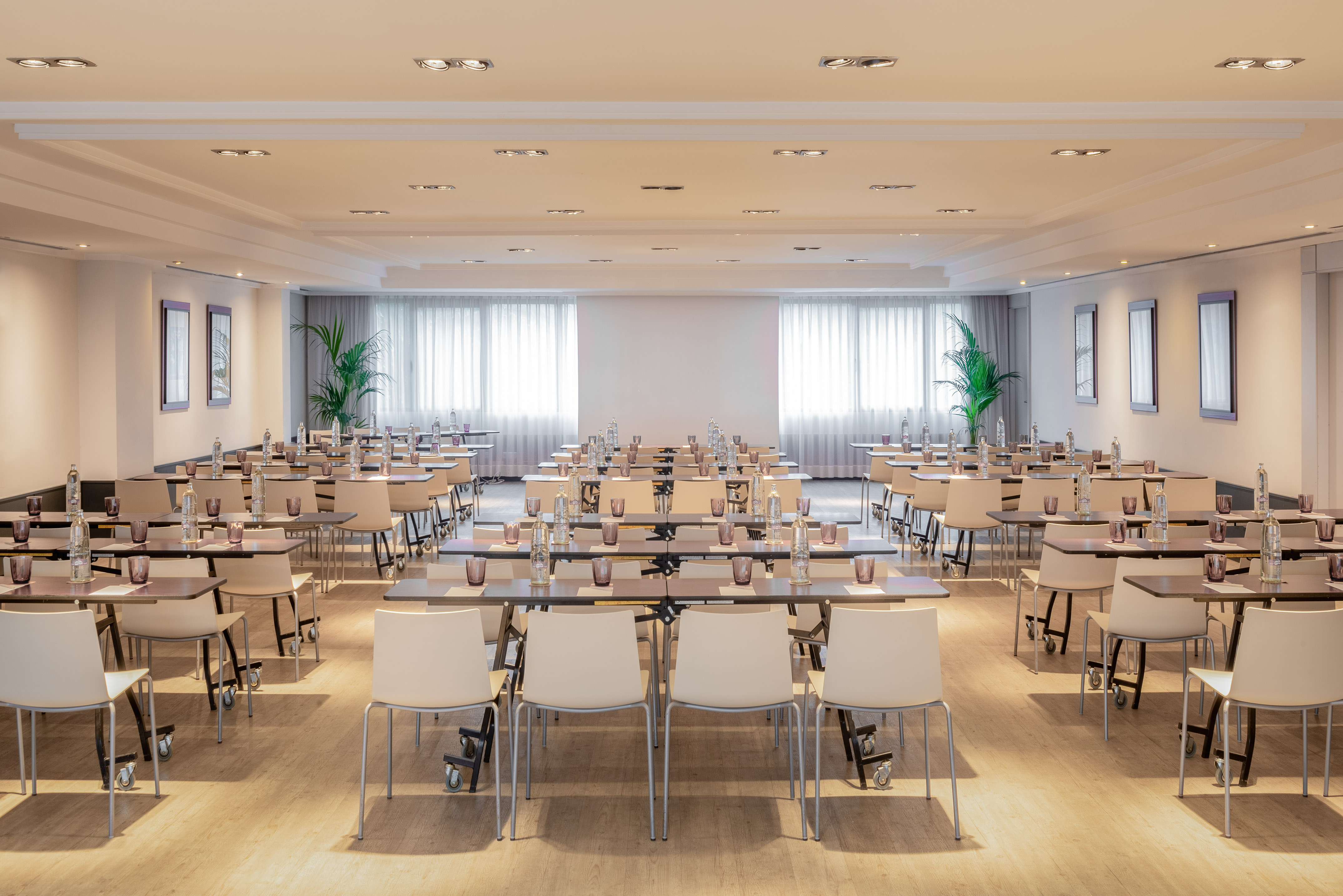 Modern conference room with tables, chairs, water, and projector screen setup.
