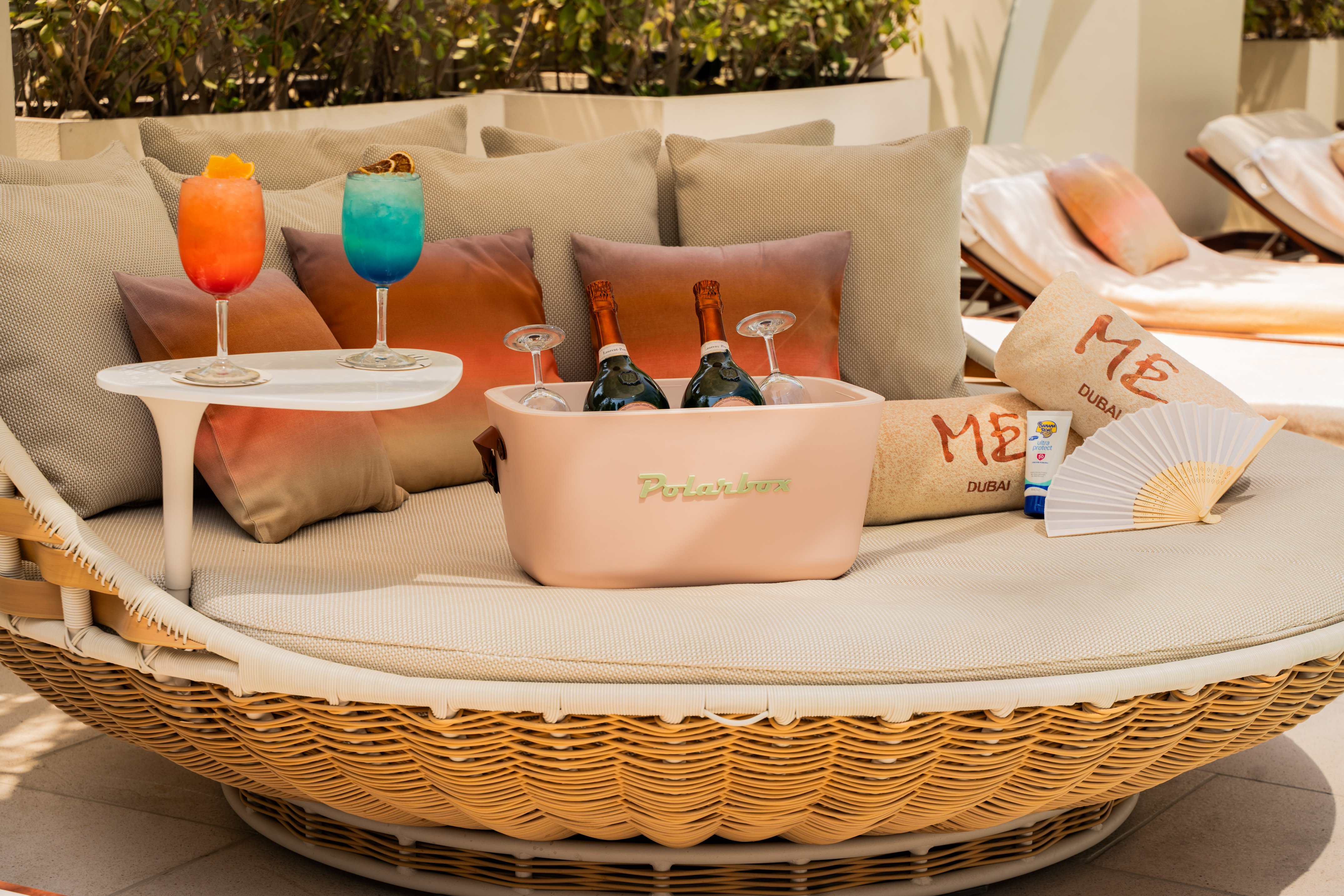Luxury outdoor daybed with colorful cocktails, champagne, and ME Dubai towels.