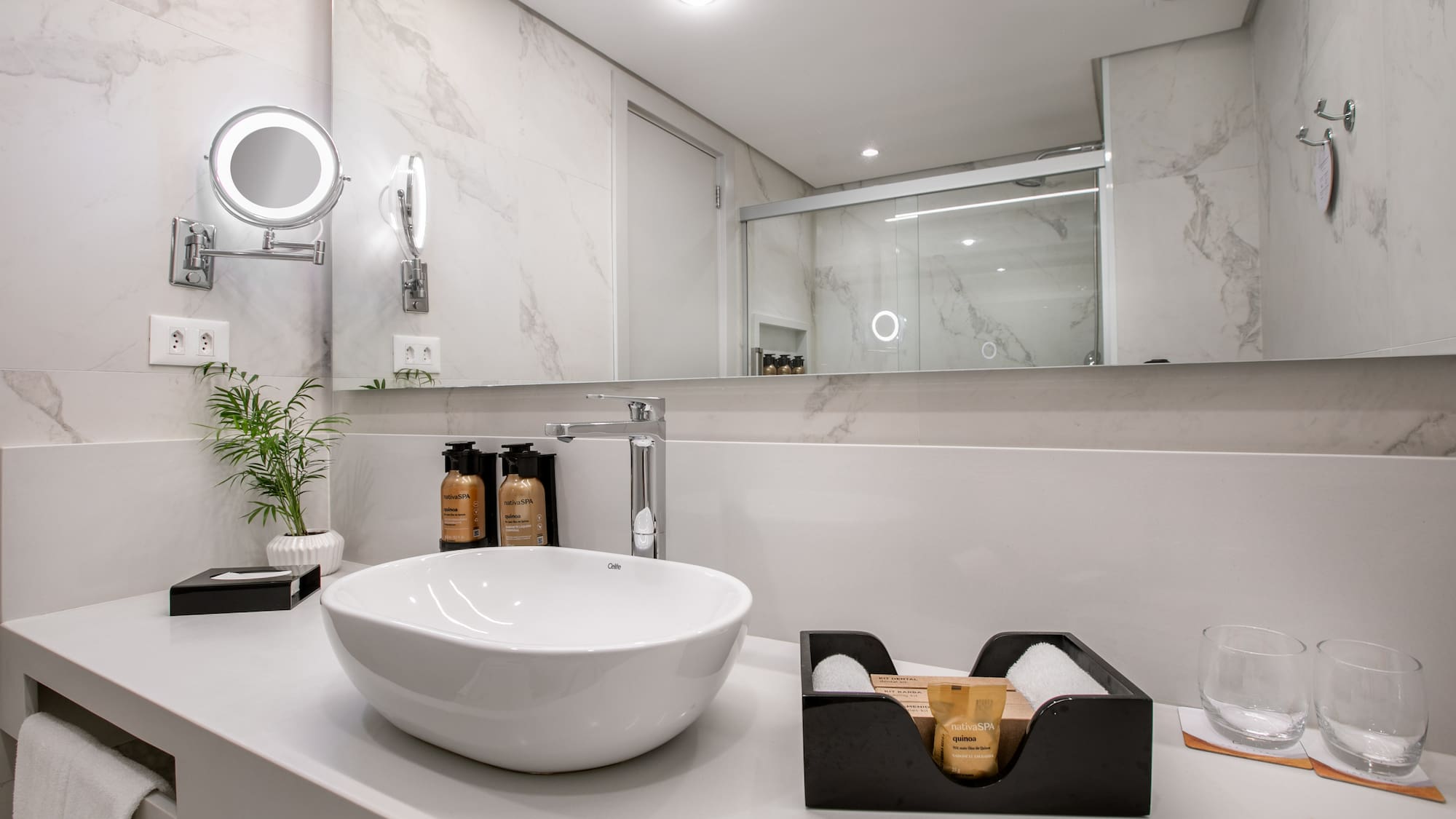 Modern hotel bathroom vanity with vessel sink, marble walls, and spa toiletries.