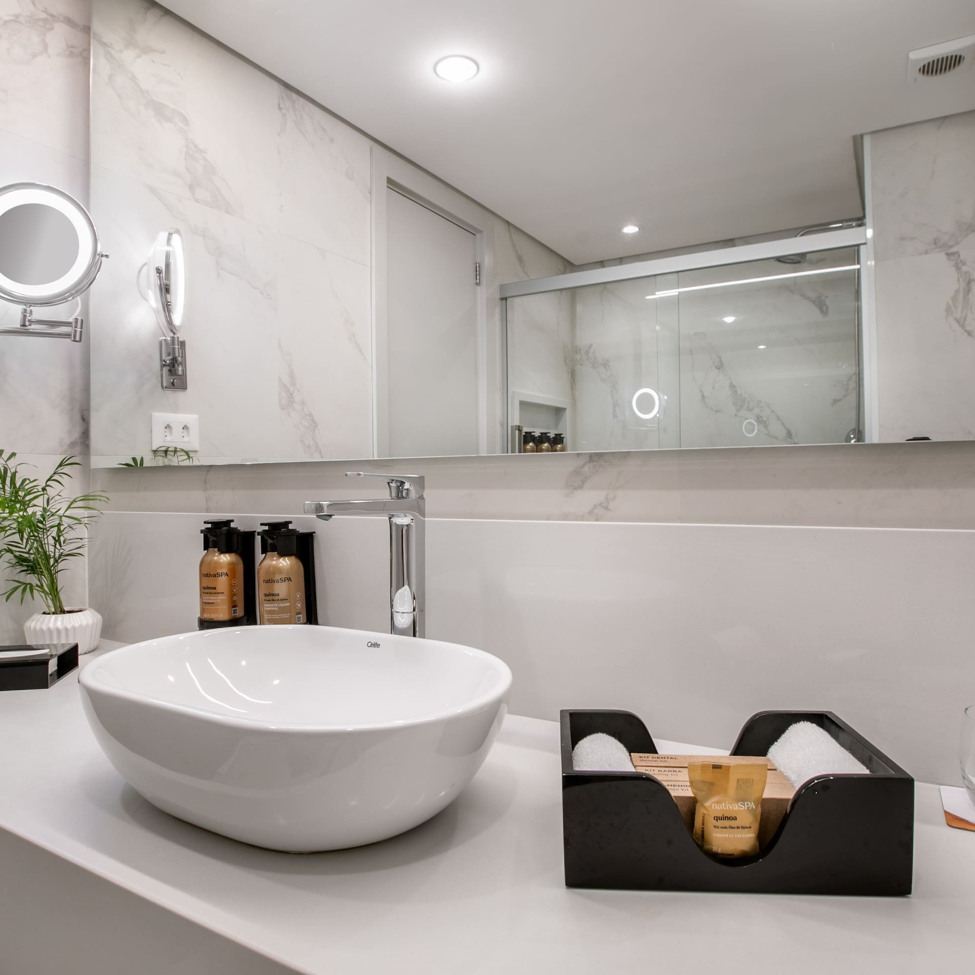 Modern bathroom vanity, white vessel sink, illuminated mirror, marble tiles.