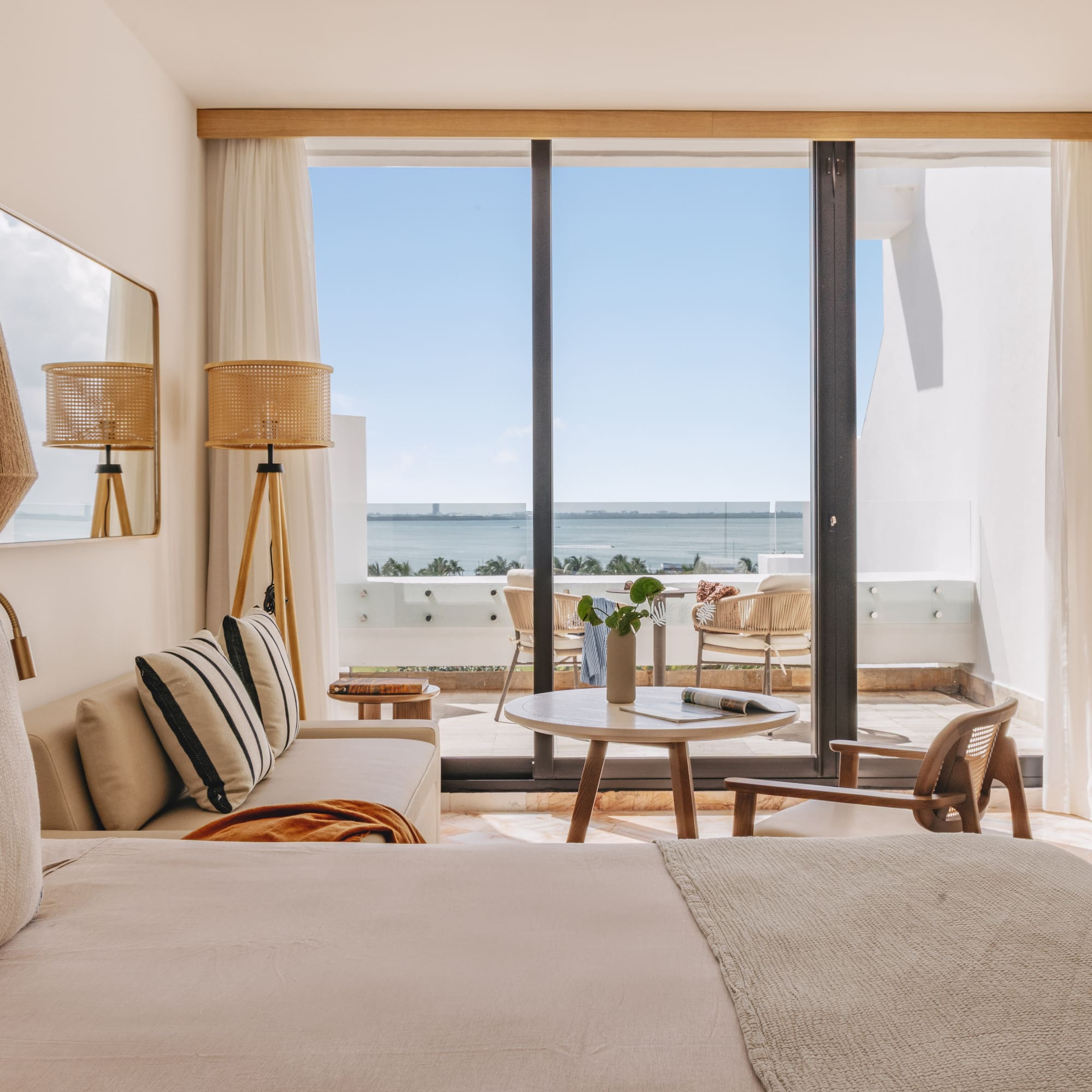 Bright hotel suite with ocean view, balcony, and contemporary coastal decor.