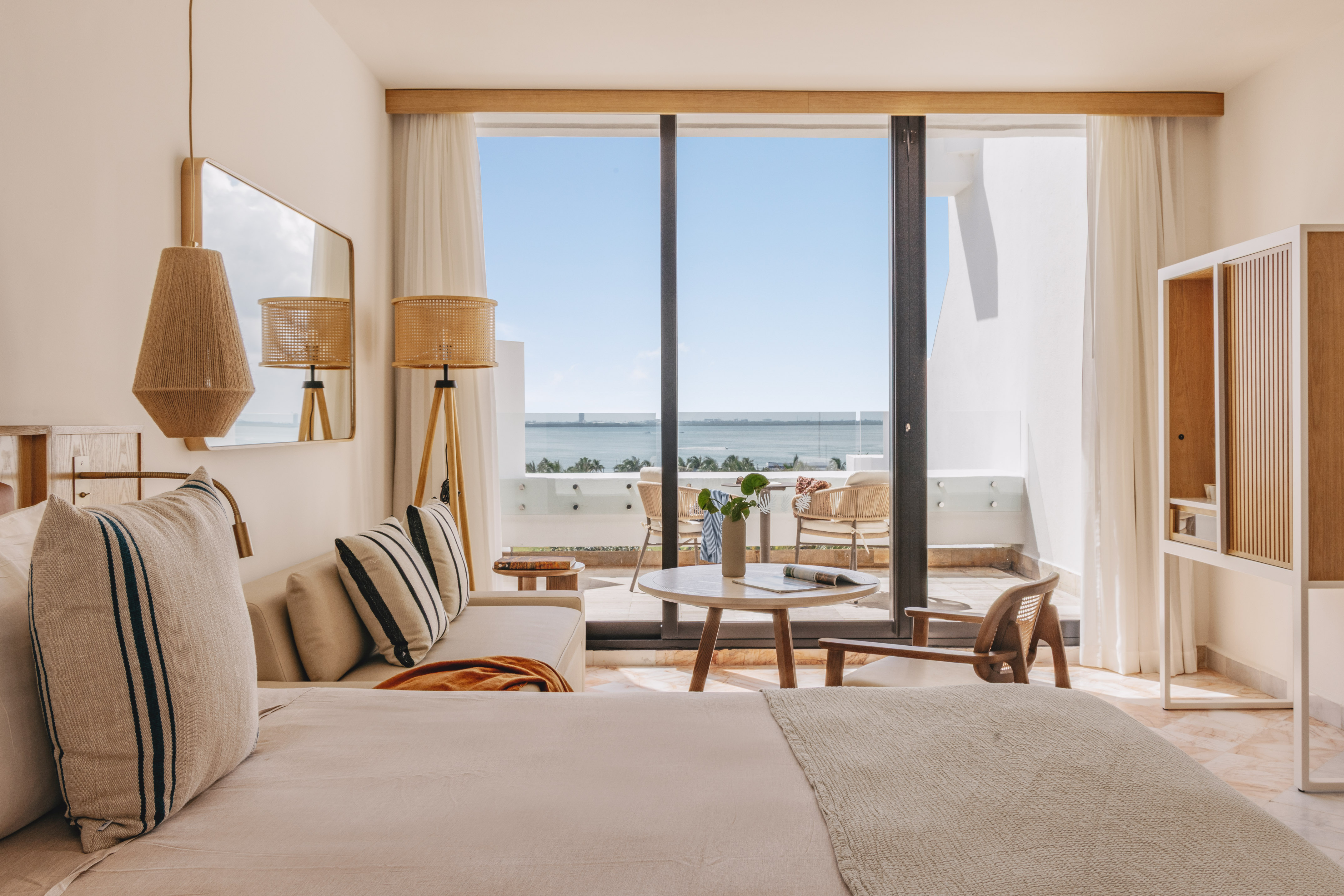 Bright hotel suite with ocean view, balcony, and contemporary coastal decor.
