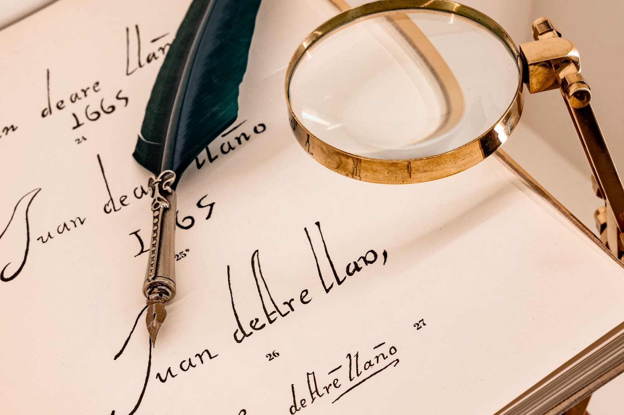 Vintage open book with quill pen, magnifying glass, and old script.