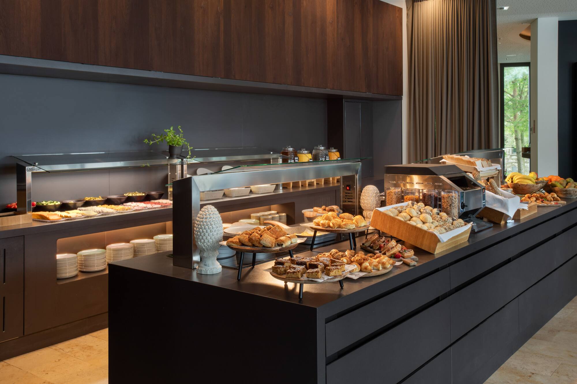 Hotel breakfast buffet featuring pastries, fruit, cold cuts, and cereals.