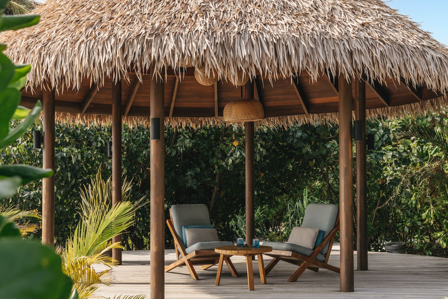 a straw hut with chairs and a table