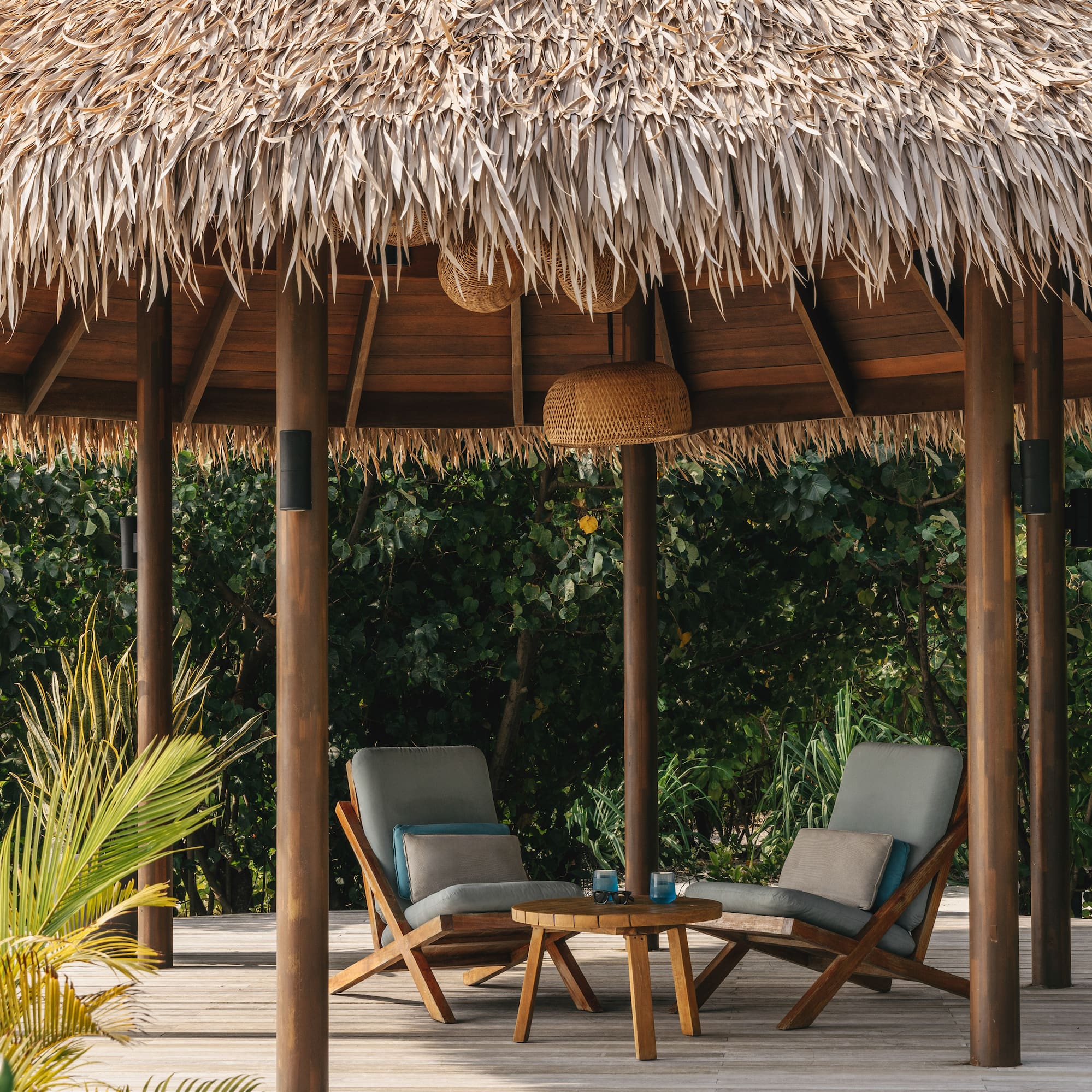 a straw hut with chairs and a table