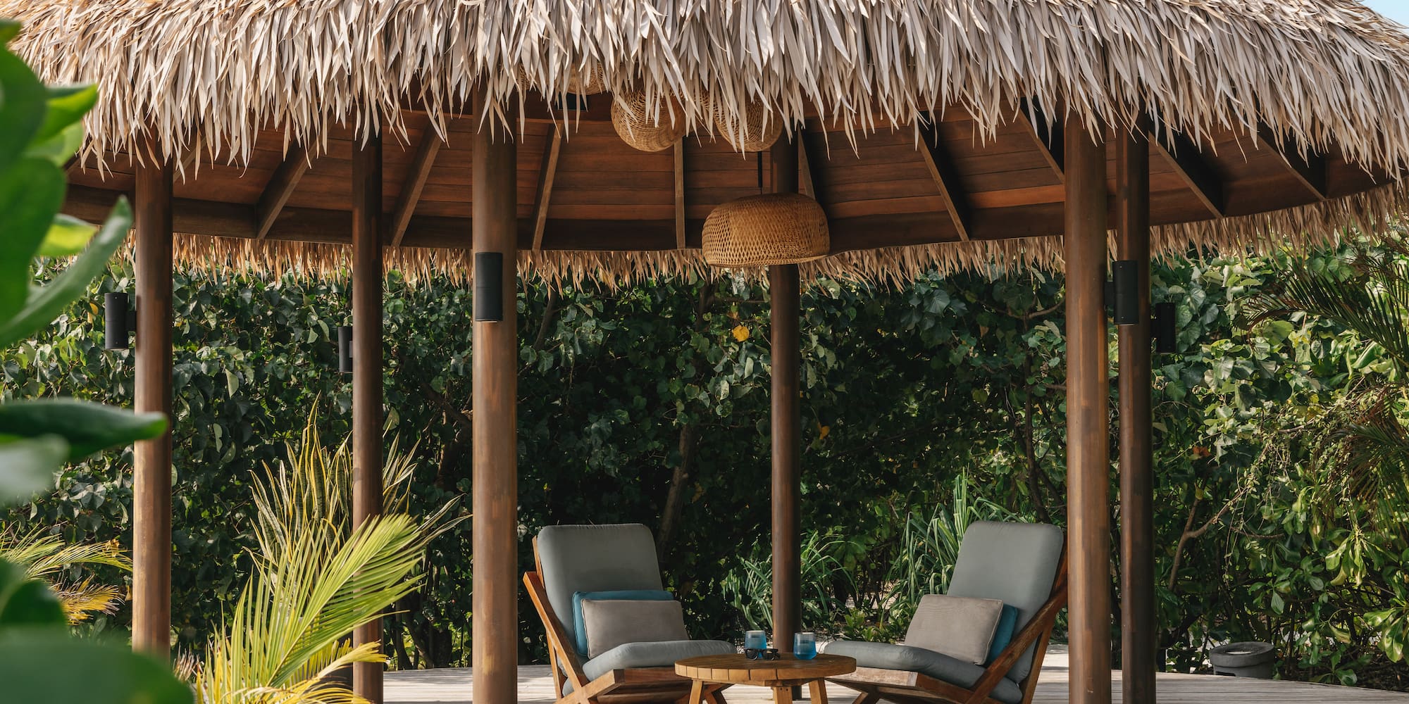 a straw hut with chairs and a table