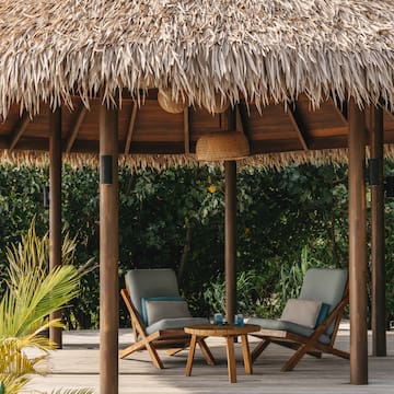 a straw hut with chairs and a table