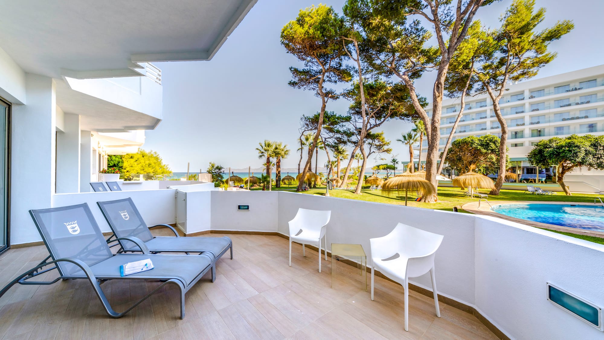 a deck with chairs and a pool in the background