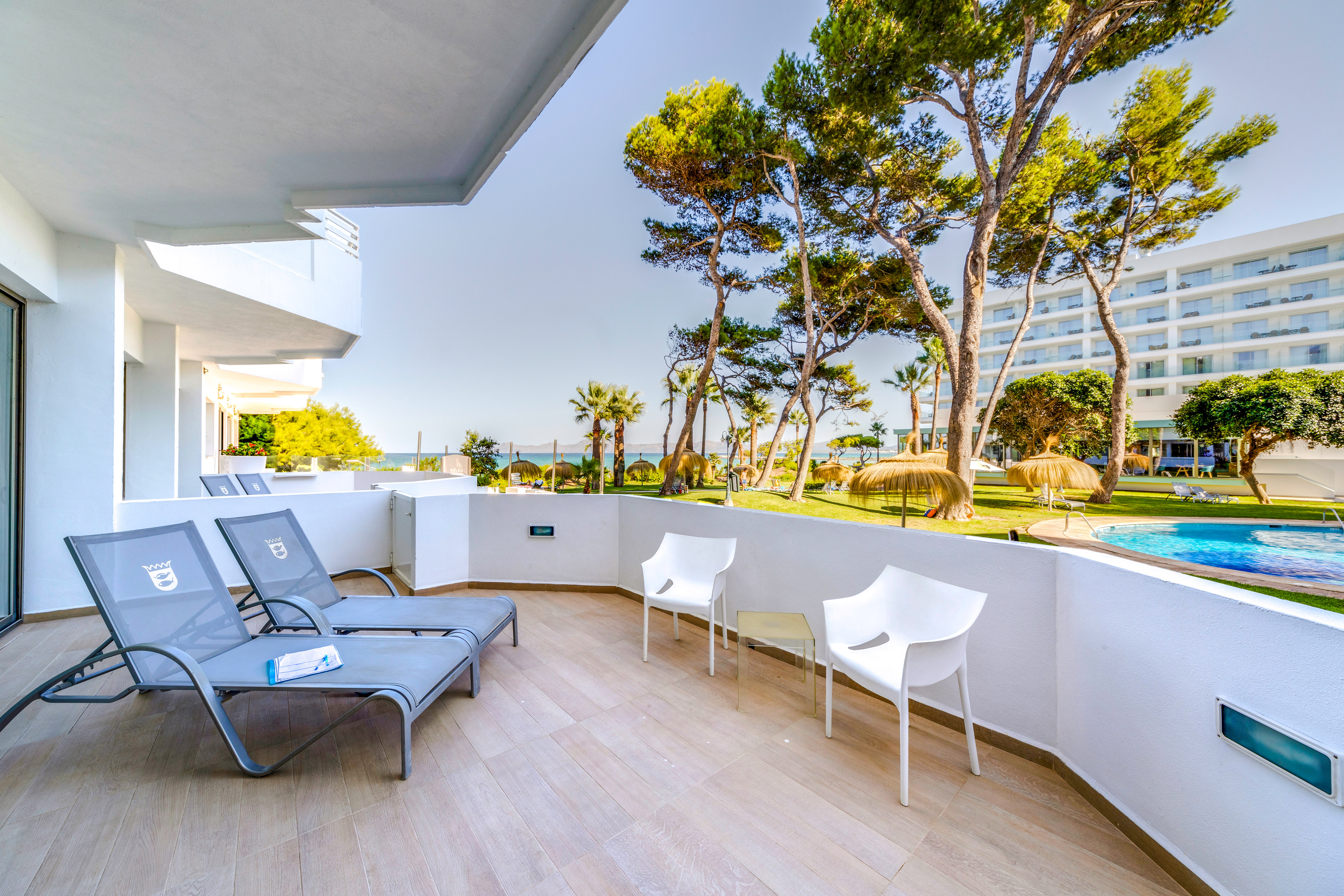a deck with chairs and a pool in the background