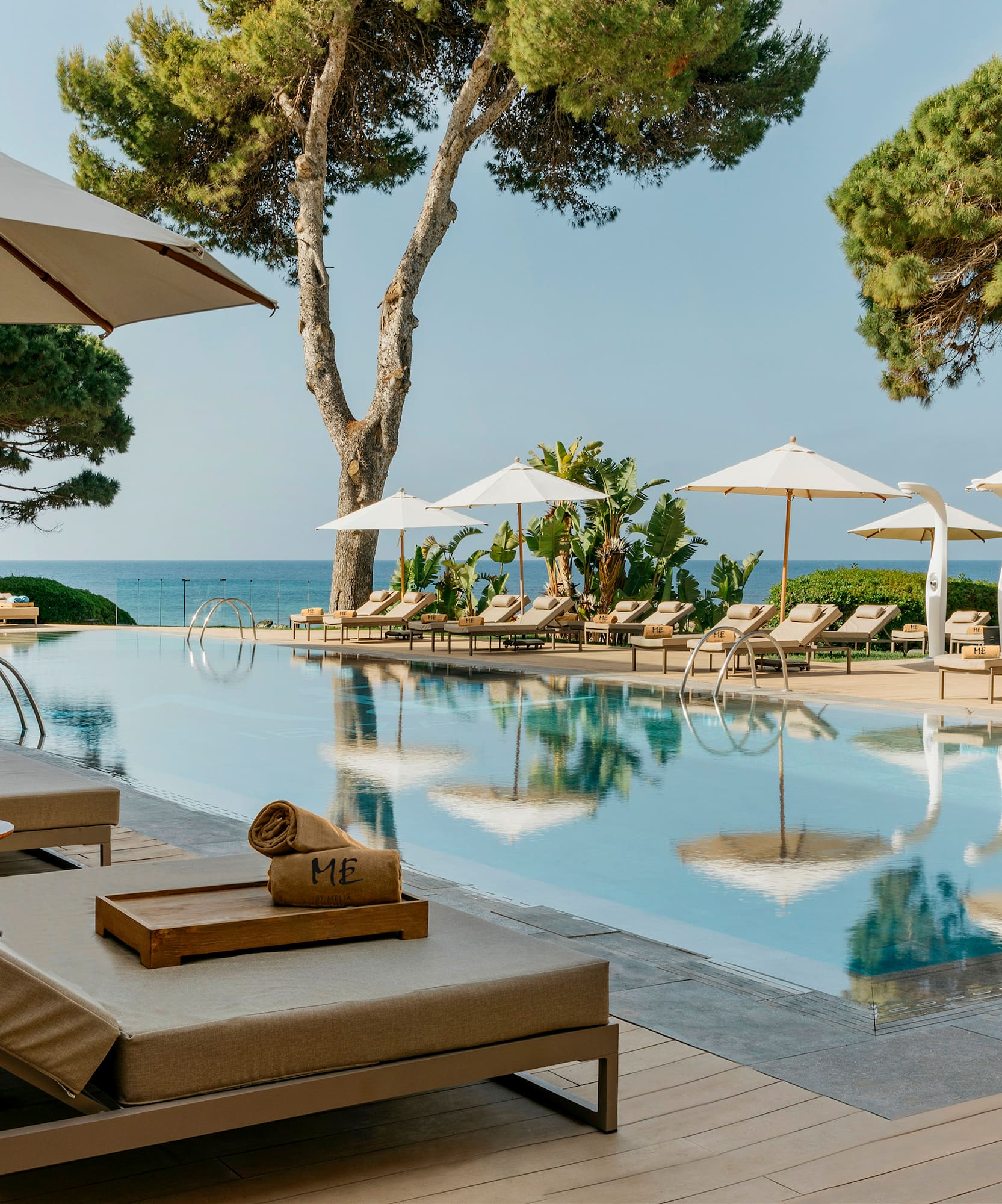 a pool with umbrellas and chairs and trees