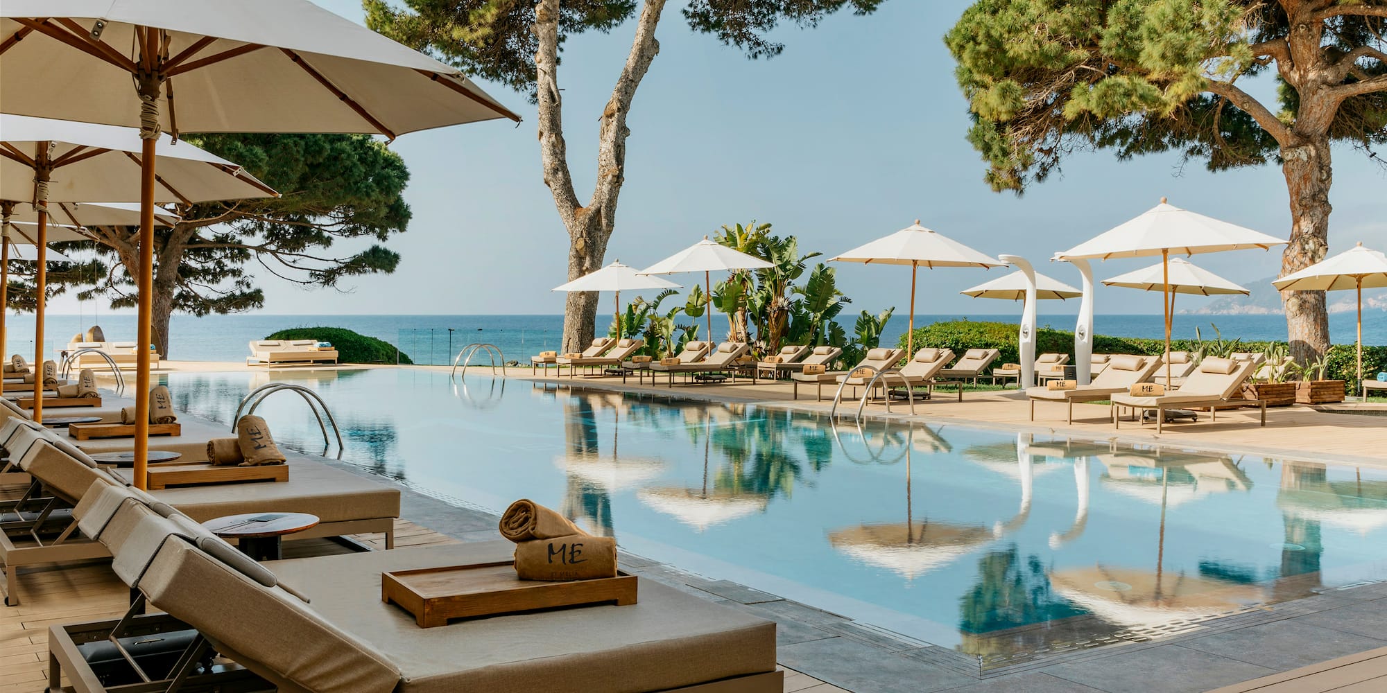 a pool with umbrellas and chairs and trees