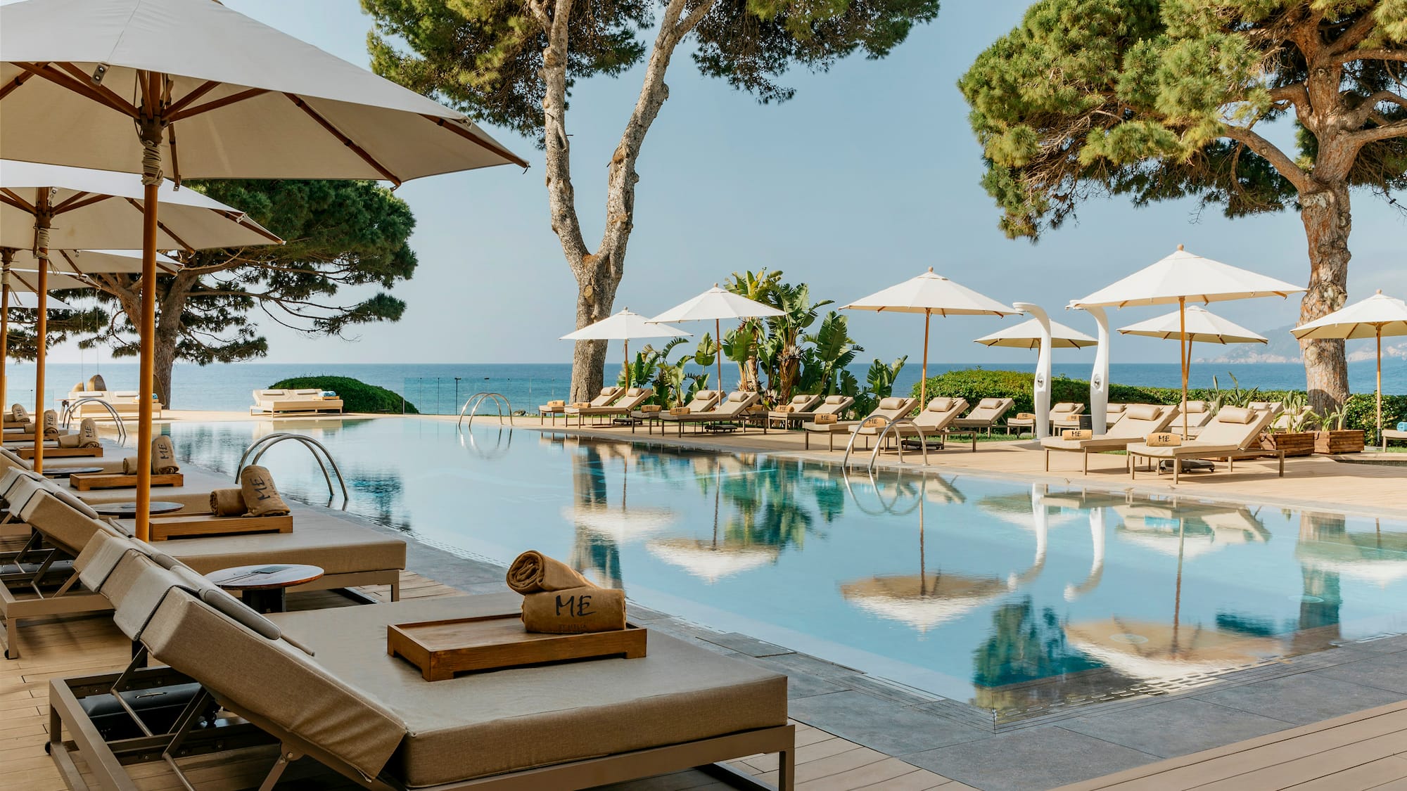 a pool with umbrellas and chairs and trees