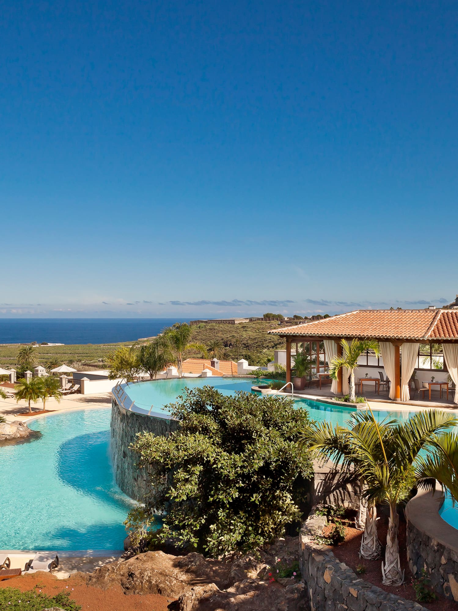 a pool with a building and a beach in the background