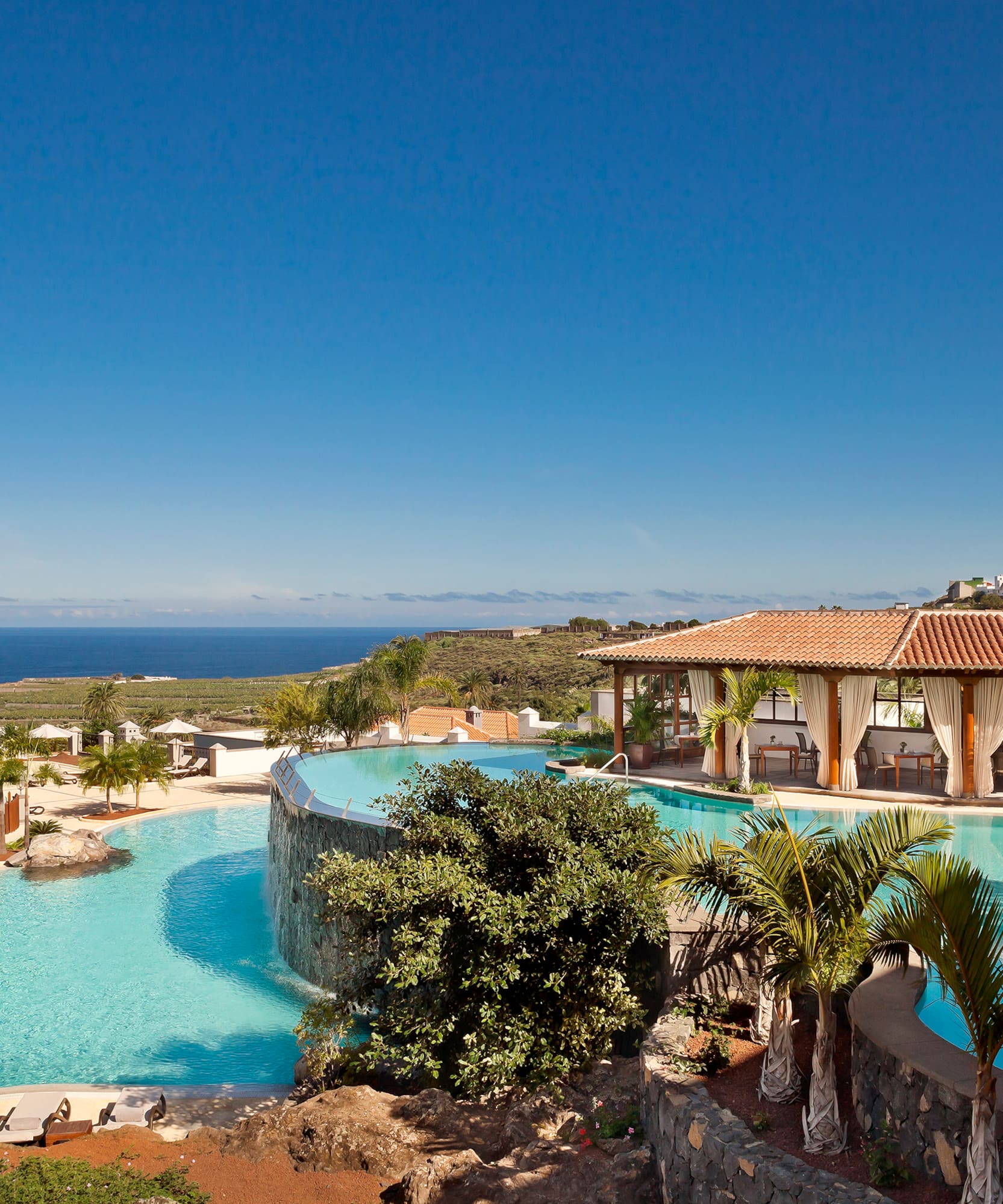 a pool with a building and a beach in the background