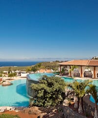 a pool with a building and a beach in the background