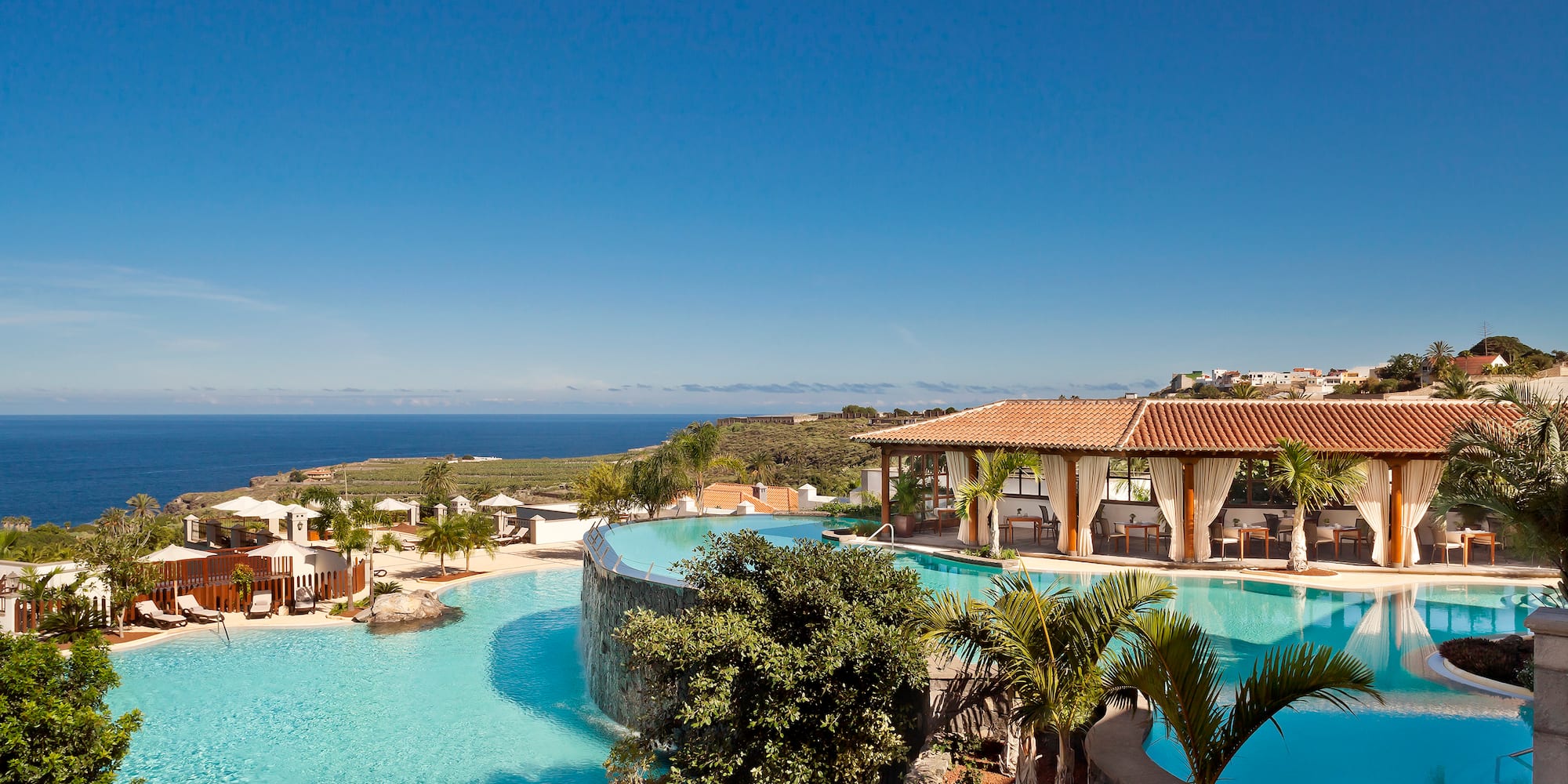 a pool with a building and a beach in the background