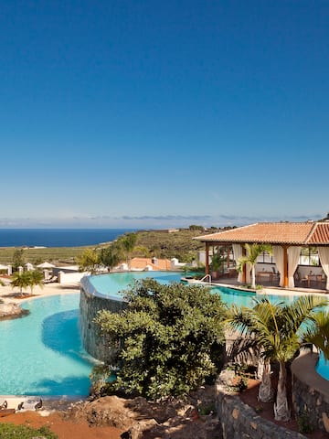 a pool with a building and a beach in the background