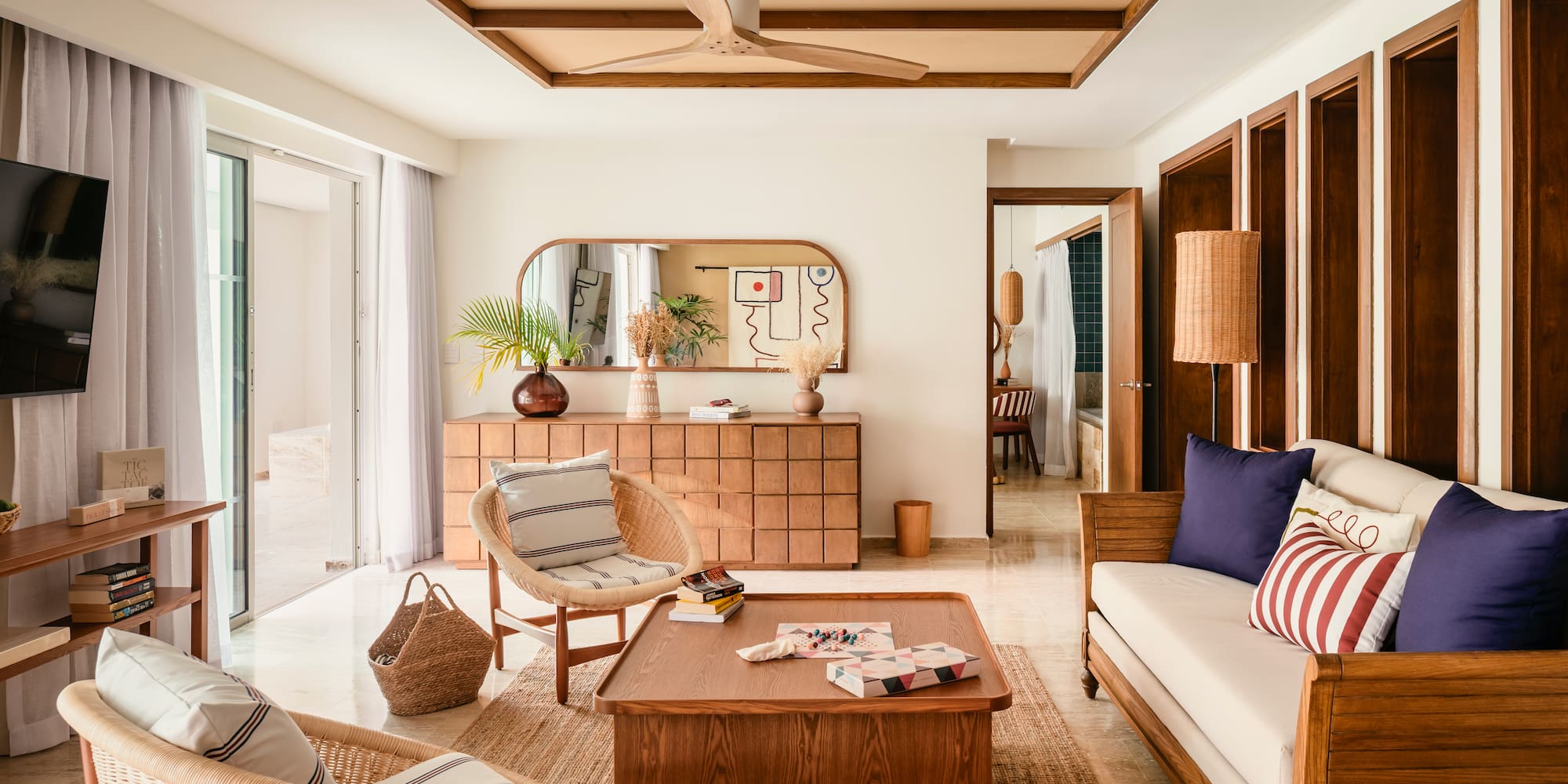 Modern tropical living room with wooden furniture, rattan accents, and ceiling fan.