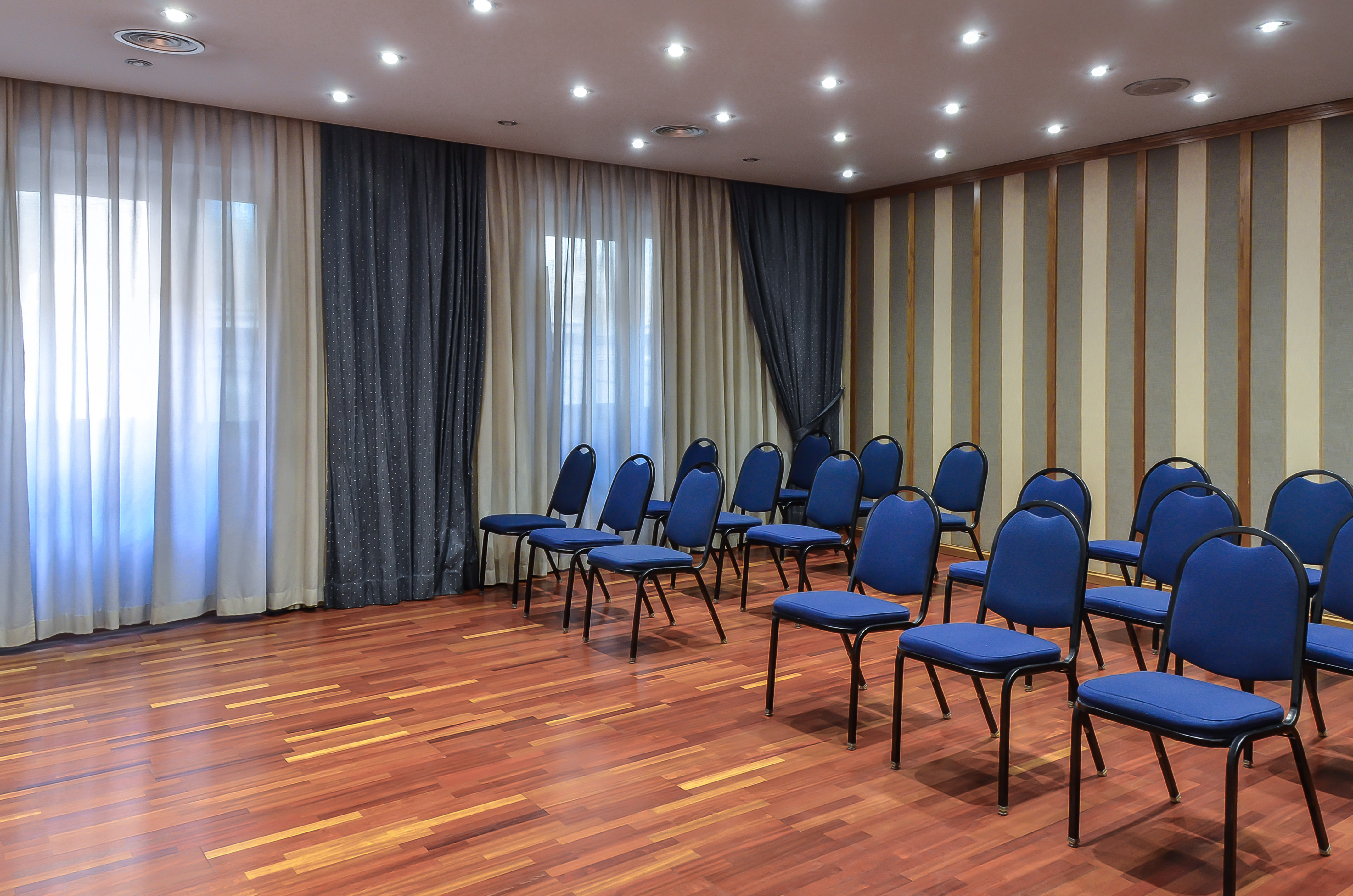 Empty conference room with blue chairs, hardwood floor, and striped walls.