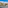 Sunny balcony view of tropical resort with palm trees, apartments, and mountains.