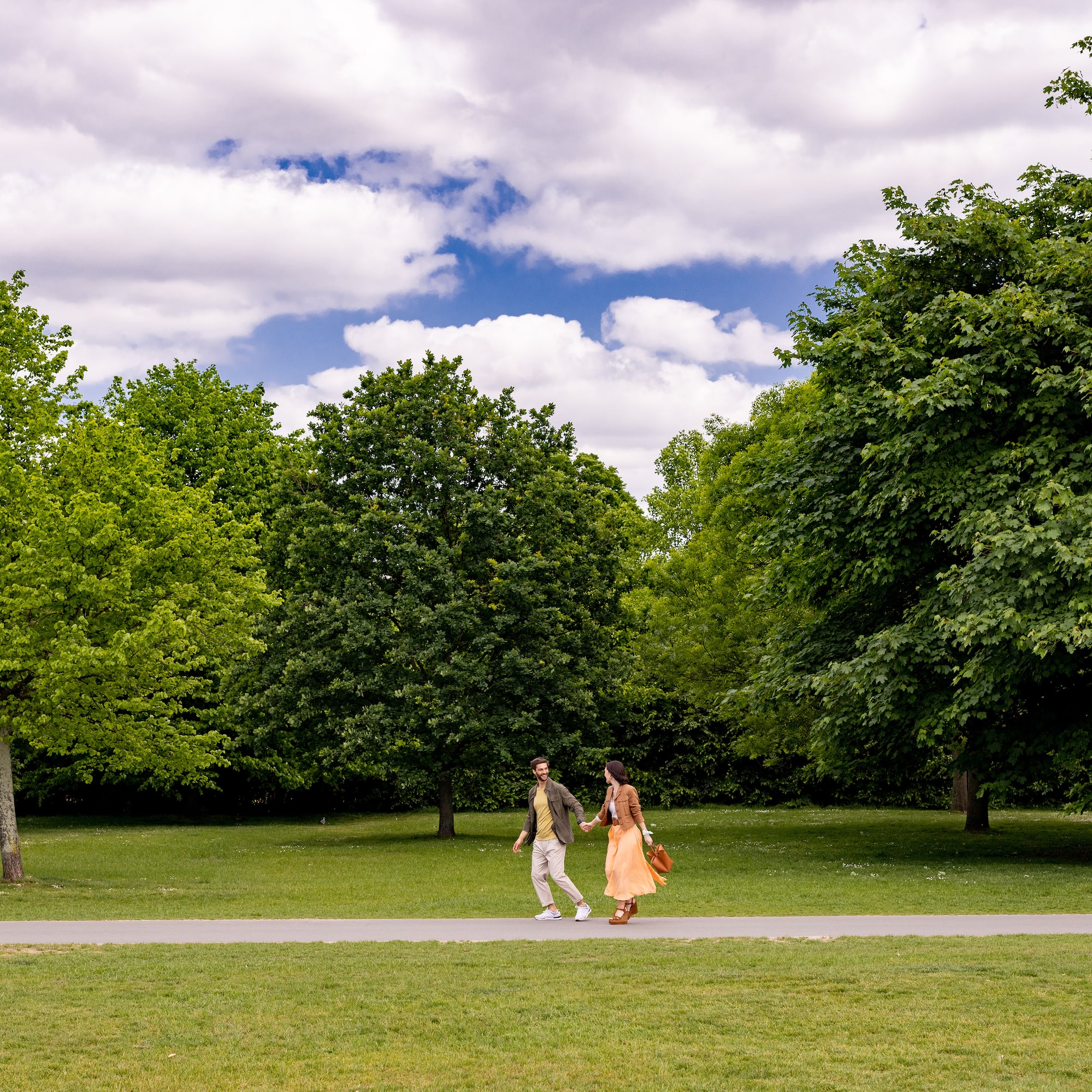 A man and a woman stroll along a path in a park.
