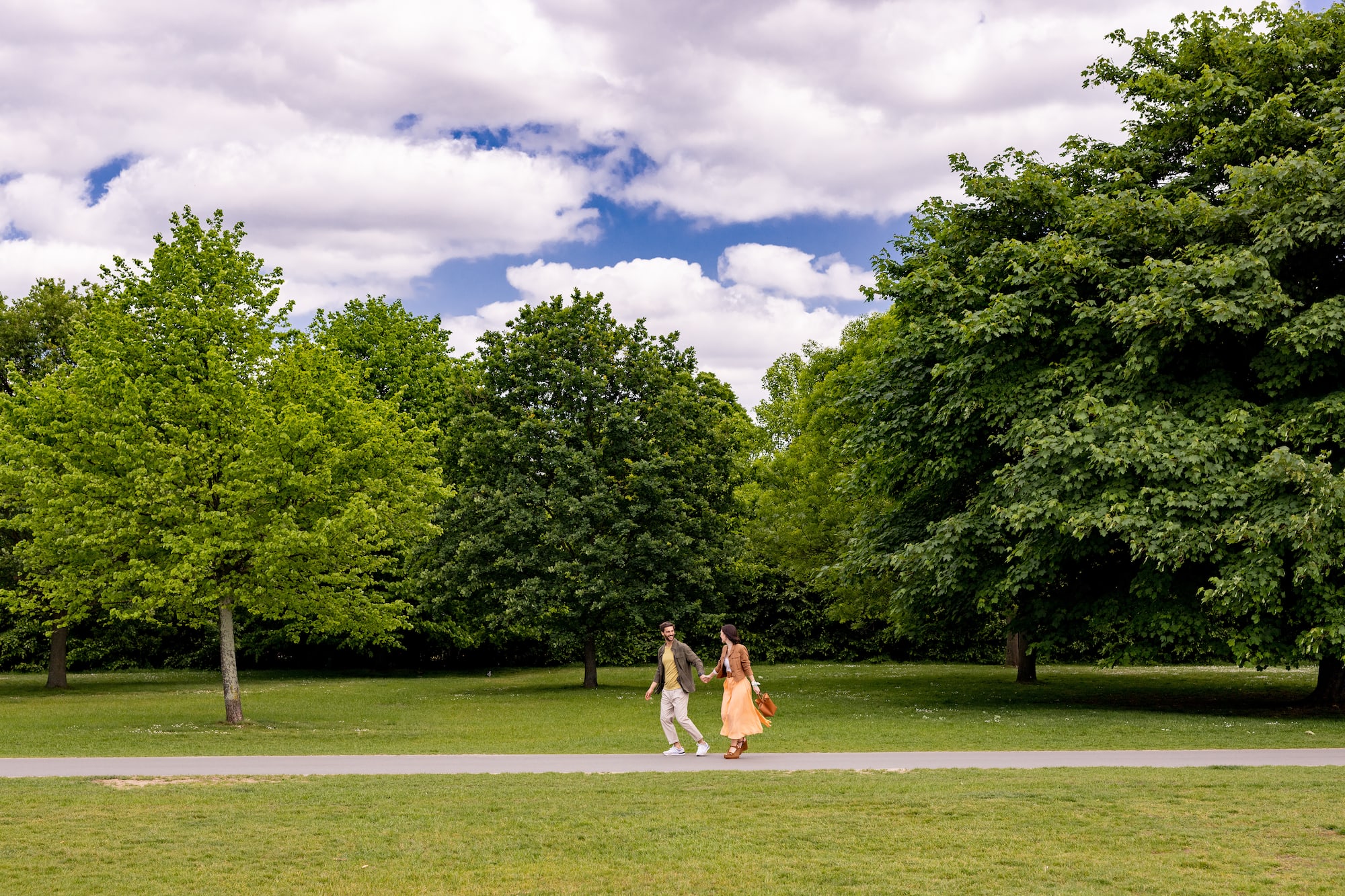 A man and a woman stroll along a path in the park.