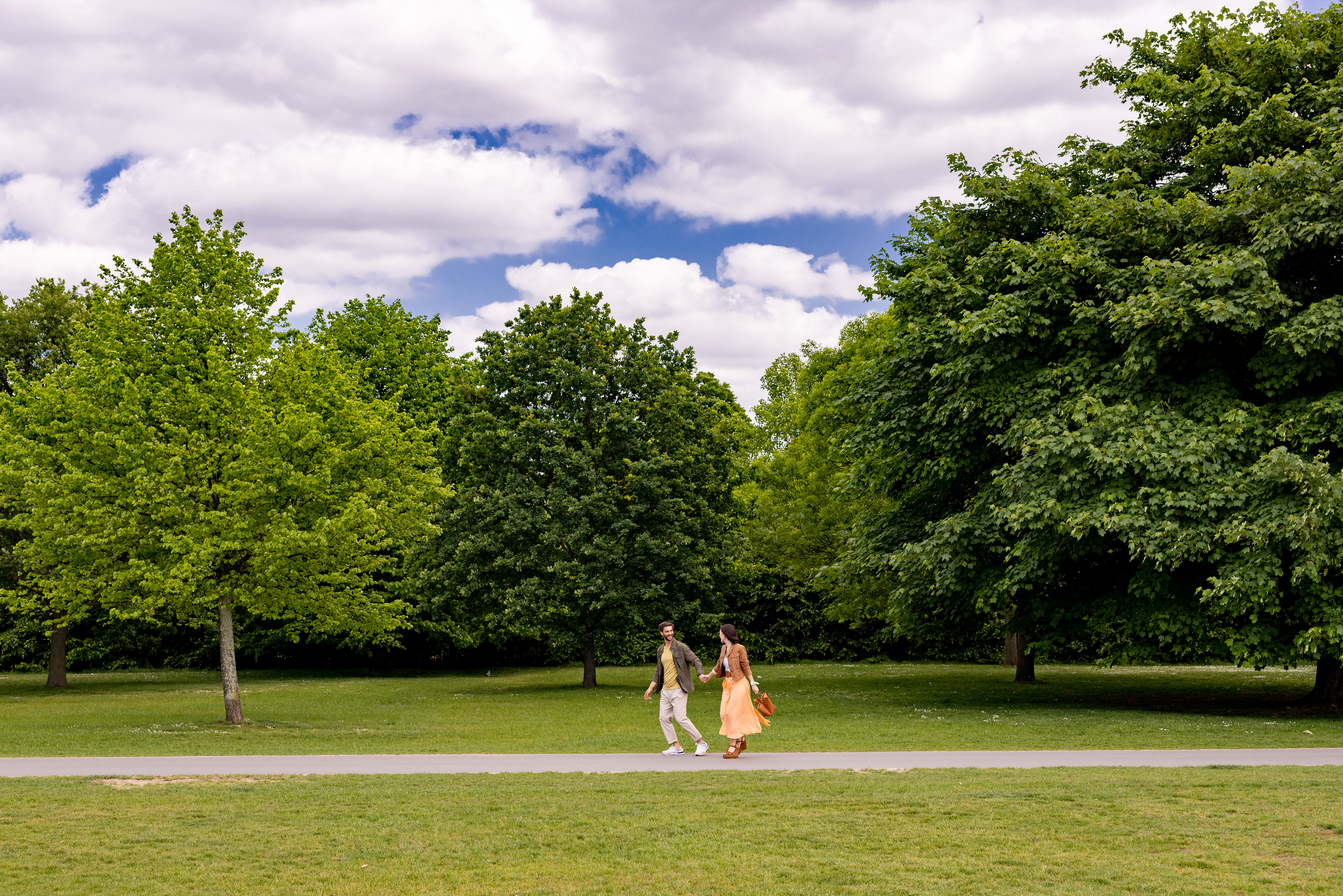 A man and a woman stroll along a path in a park.