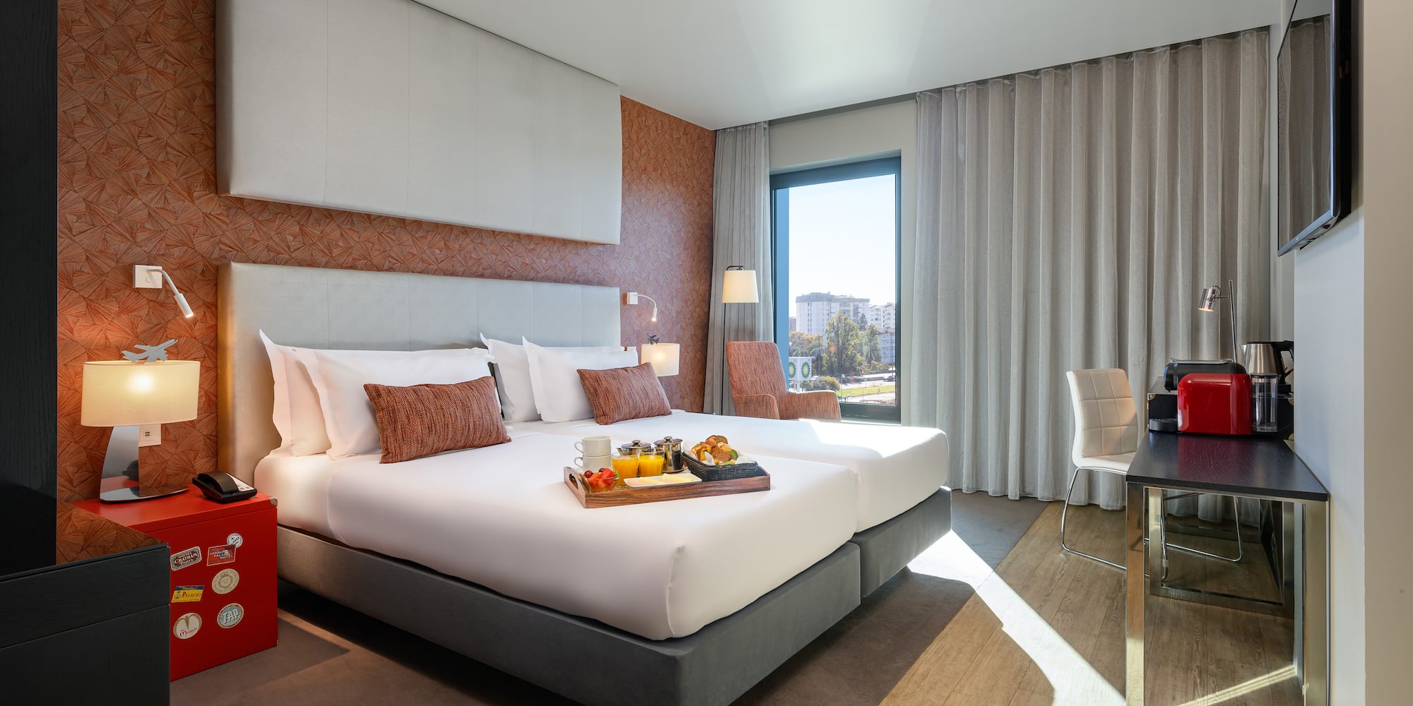 a hotel room with a tray of food on a bed