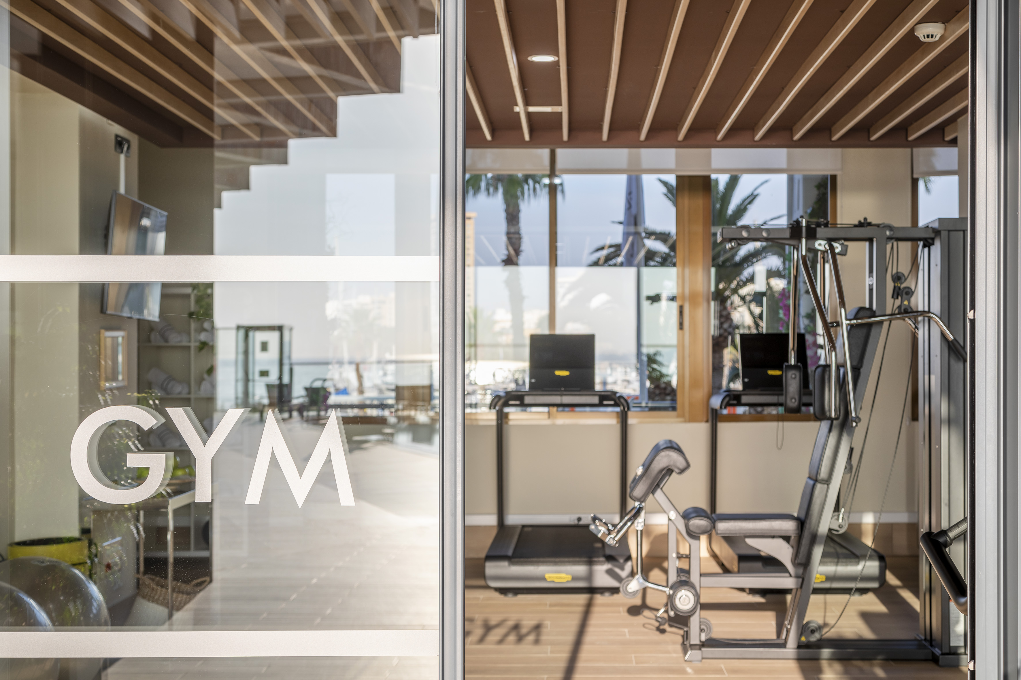 GYM on glass door of modern fitness center with treadmill and weight machine.