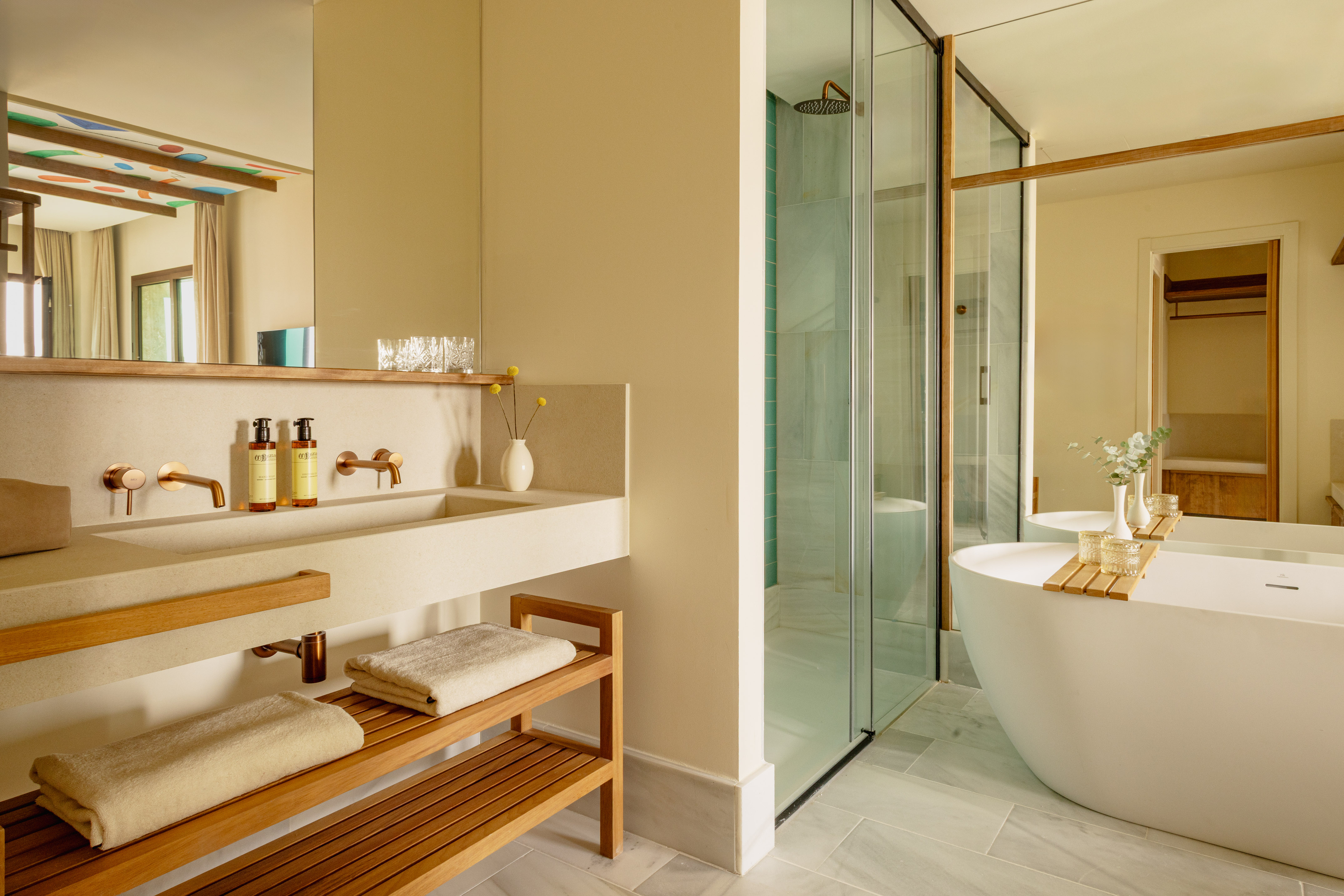 Modern bathroom with freestanding tub, glass shower, and dual stone vanity.