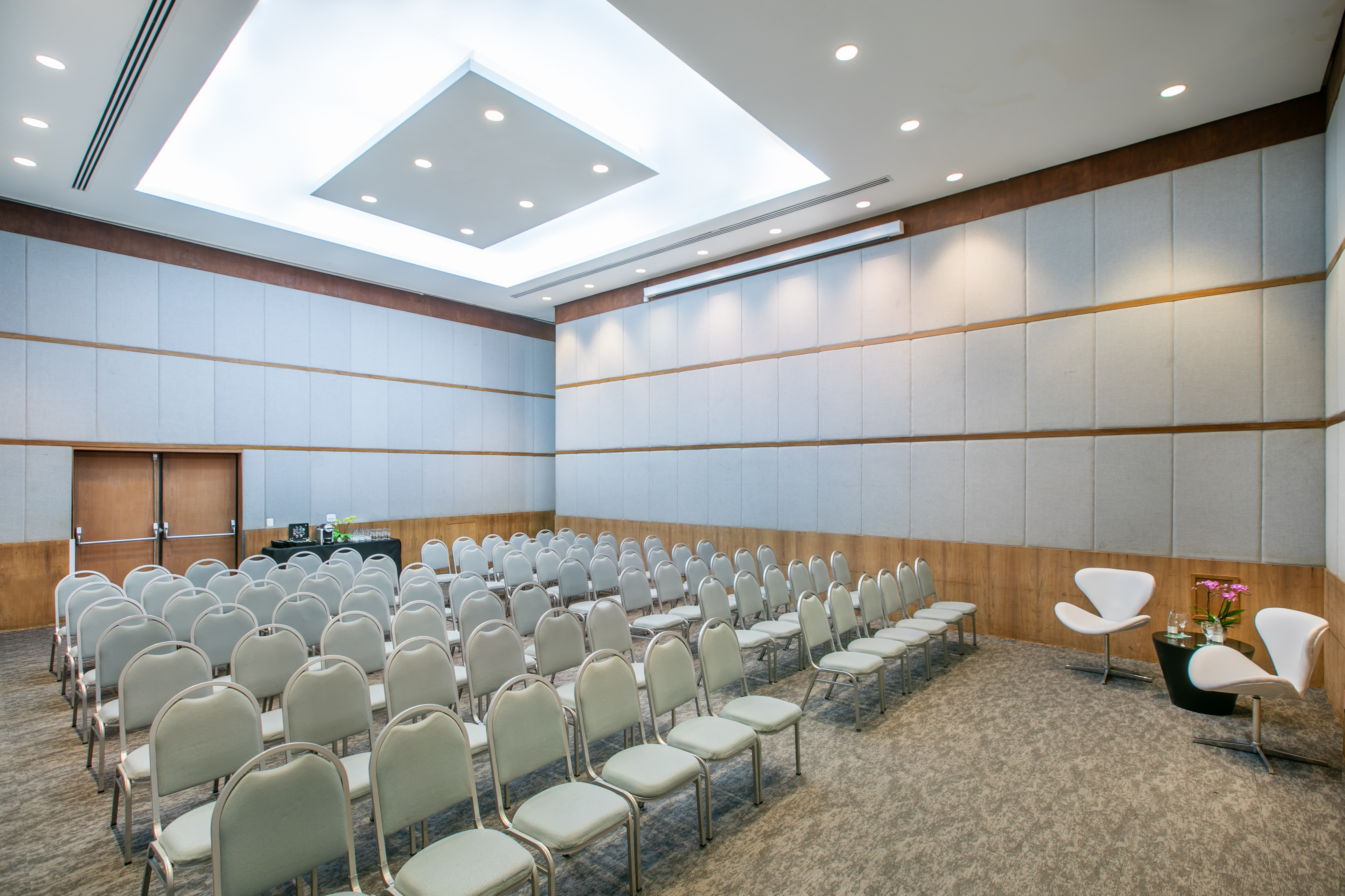 Modern event space with gray chairs in rows, acoustic walls, and recessed lighting.