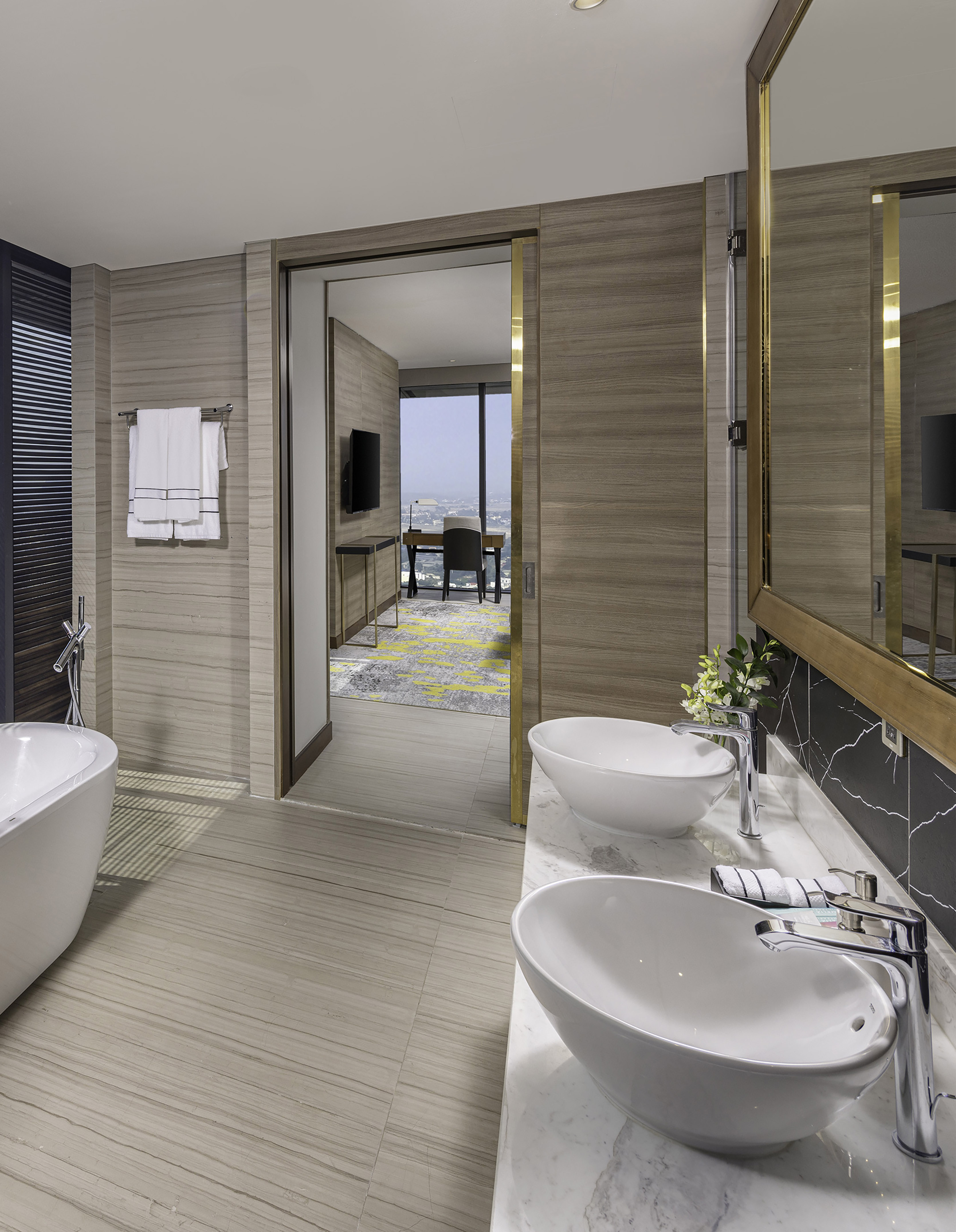 Luxury hotel bathroom with double vanity, modern tub, and city view.