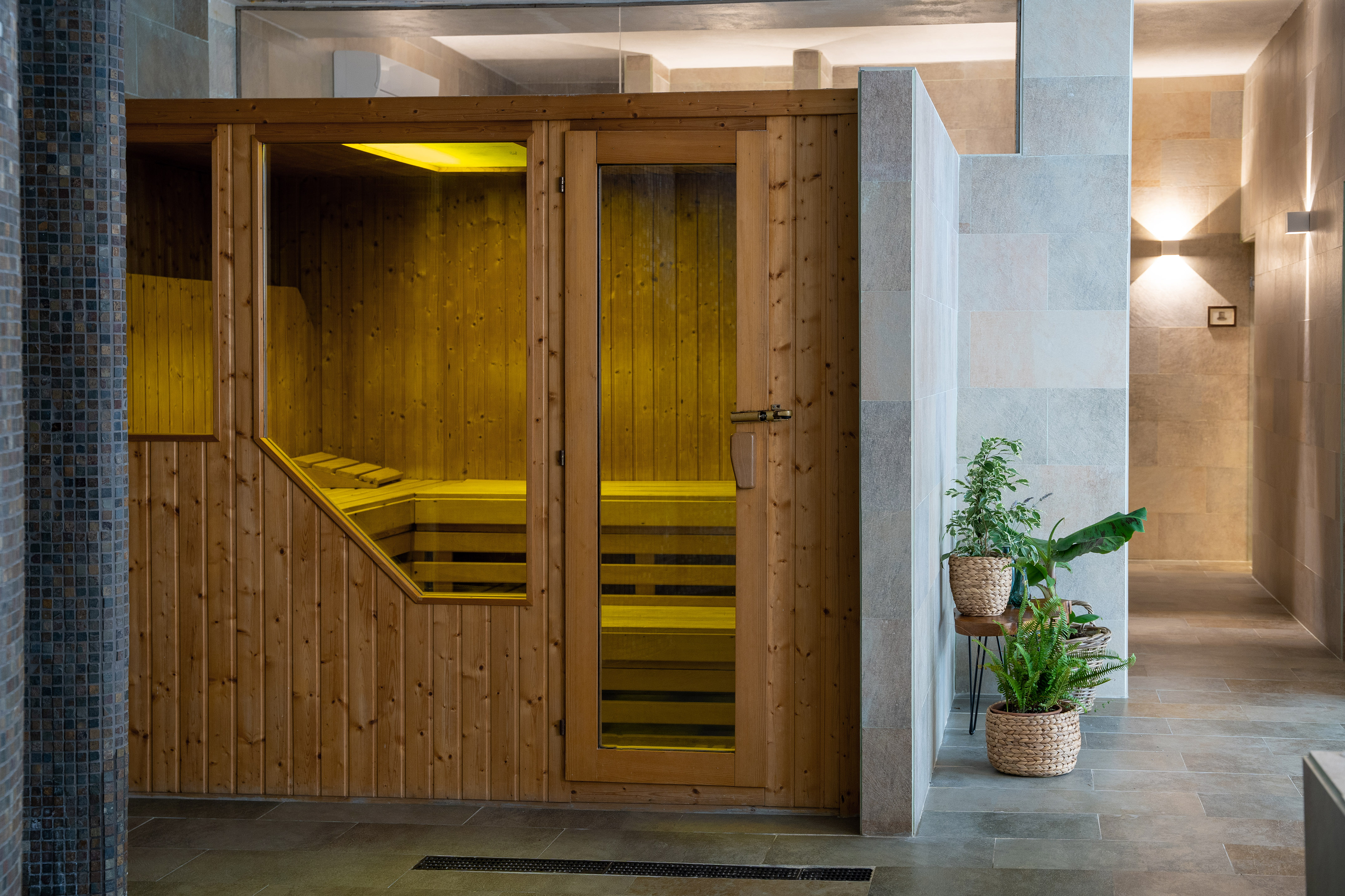 Wooden sauna cabin with warm yellow interior light in a modern spa.