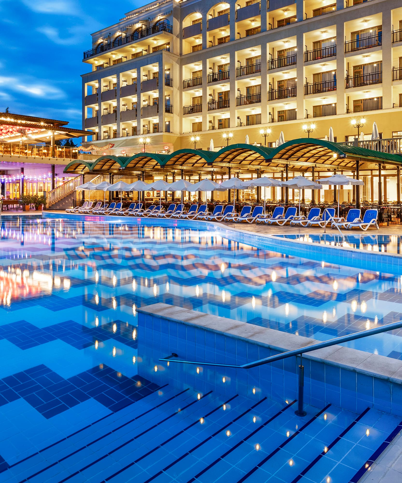a pool with chairs and a building in the background