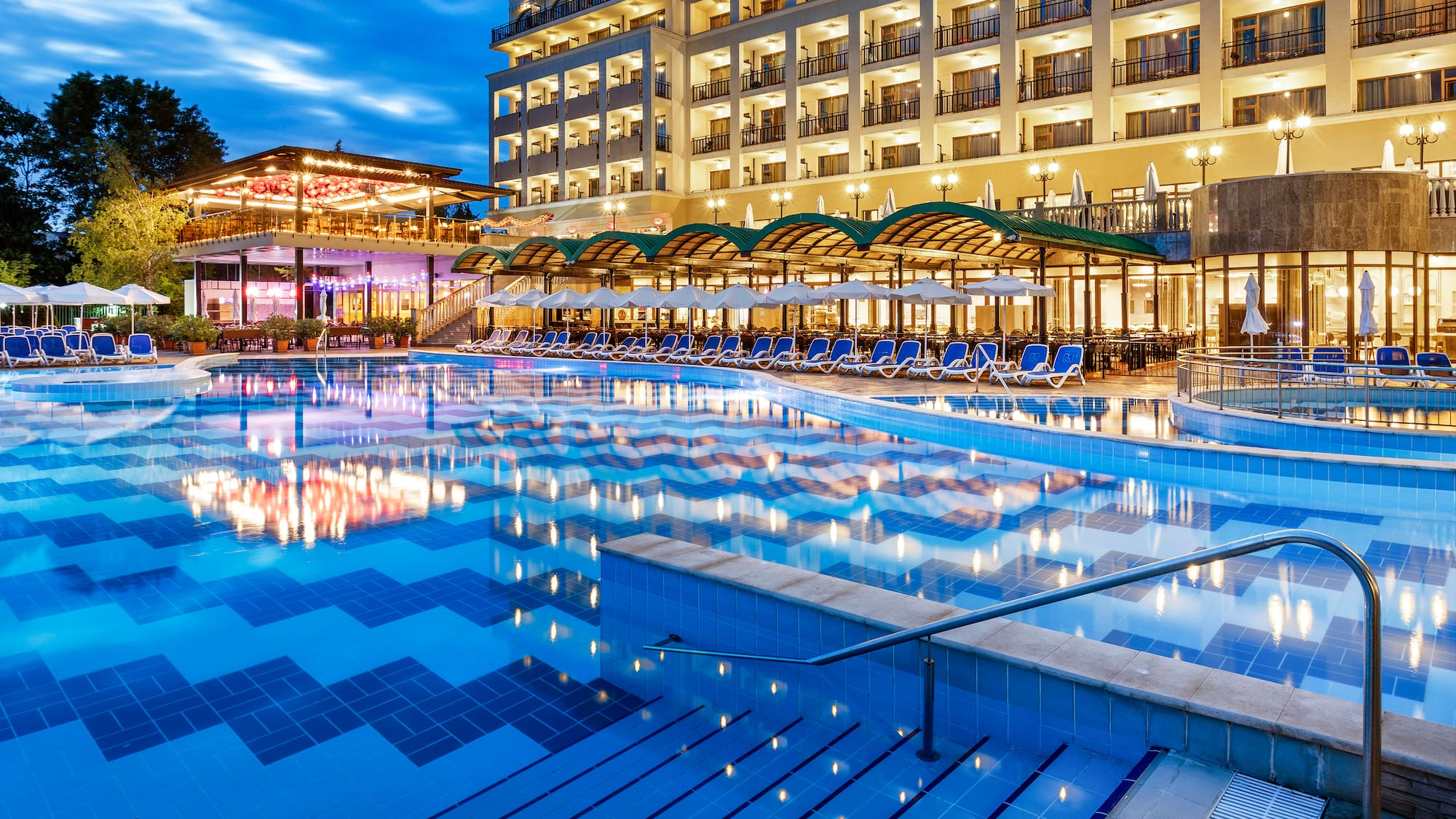 a pool with chairs and a building in the background
