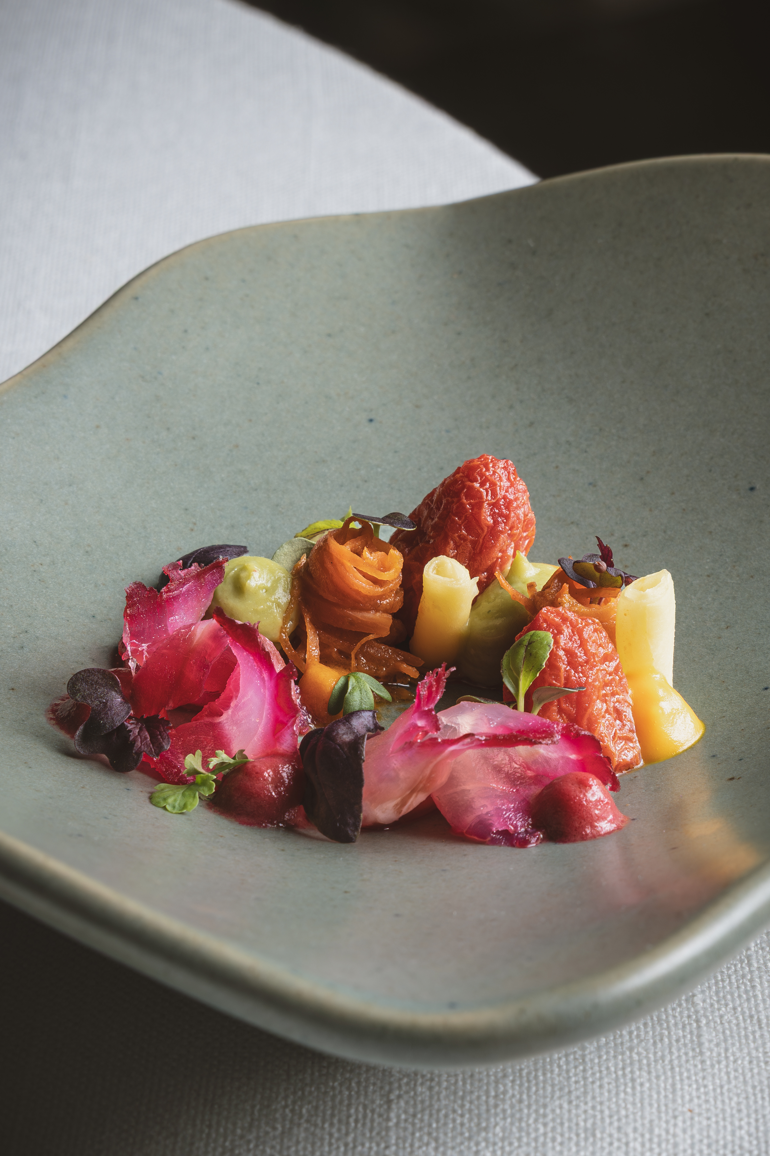 Vibrant plant-based appetizer with red beets, orange carrots, and green sauce.