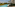 Long resort swimming pool, modern hotel with balconies, and lush palm trees.