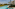 Long resort swimming pool, modern hotel with balconies, and lush palm trees.