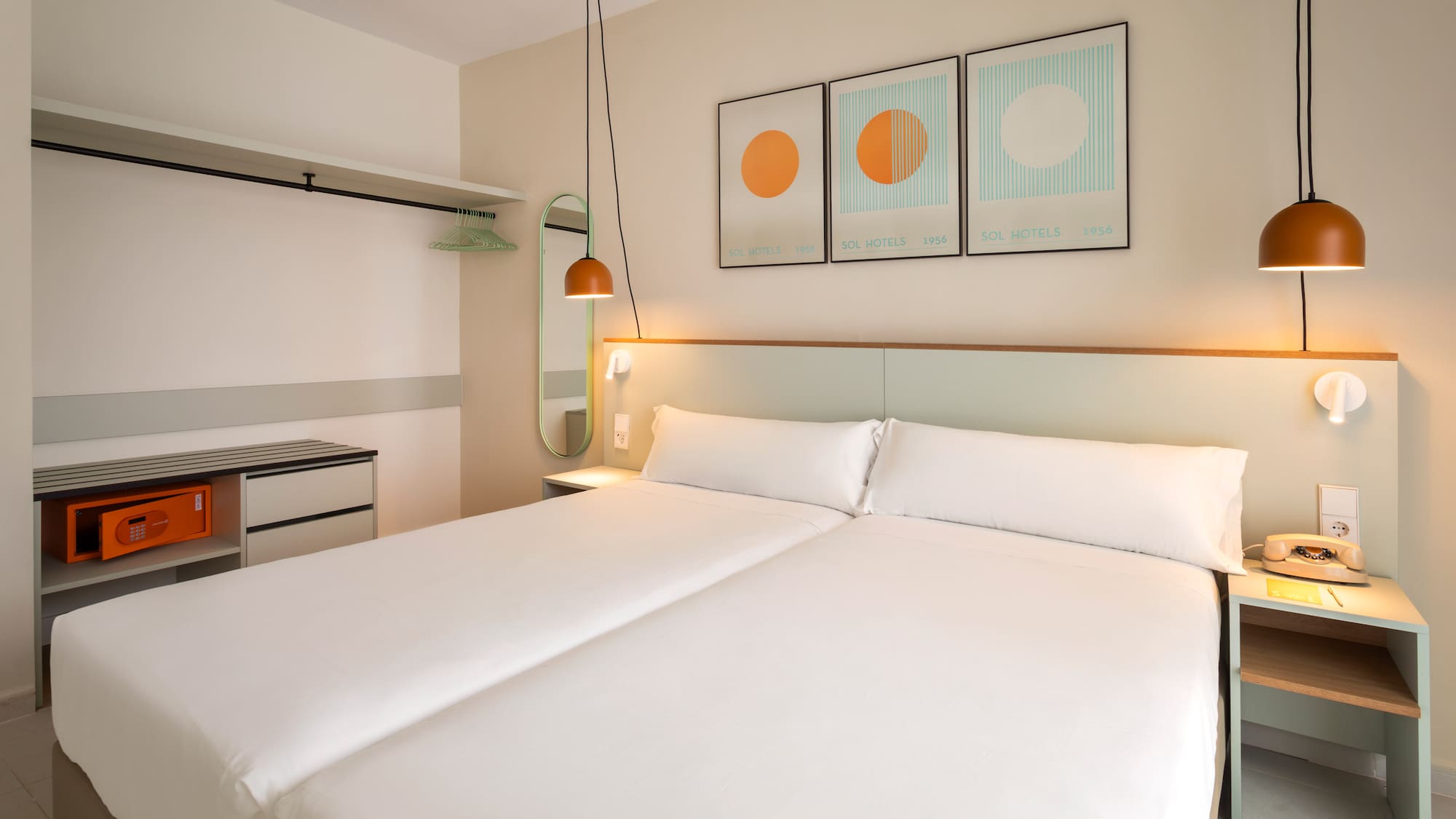 Modern hotel room with twin beds, minimalist decor, and wardrobe with safe.