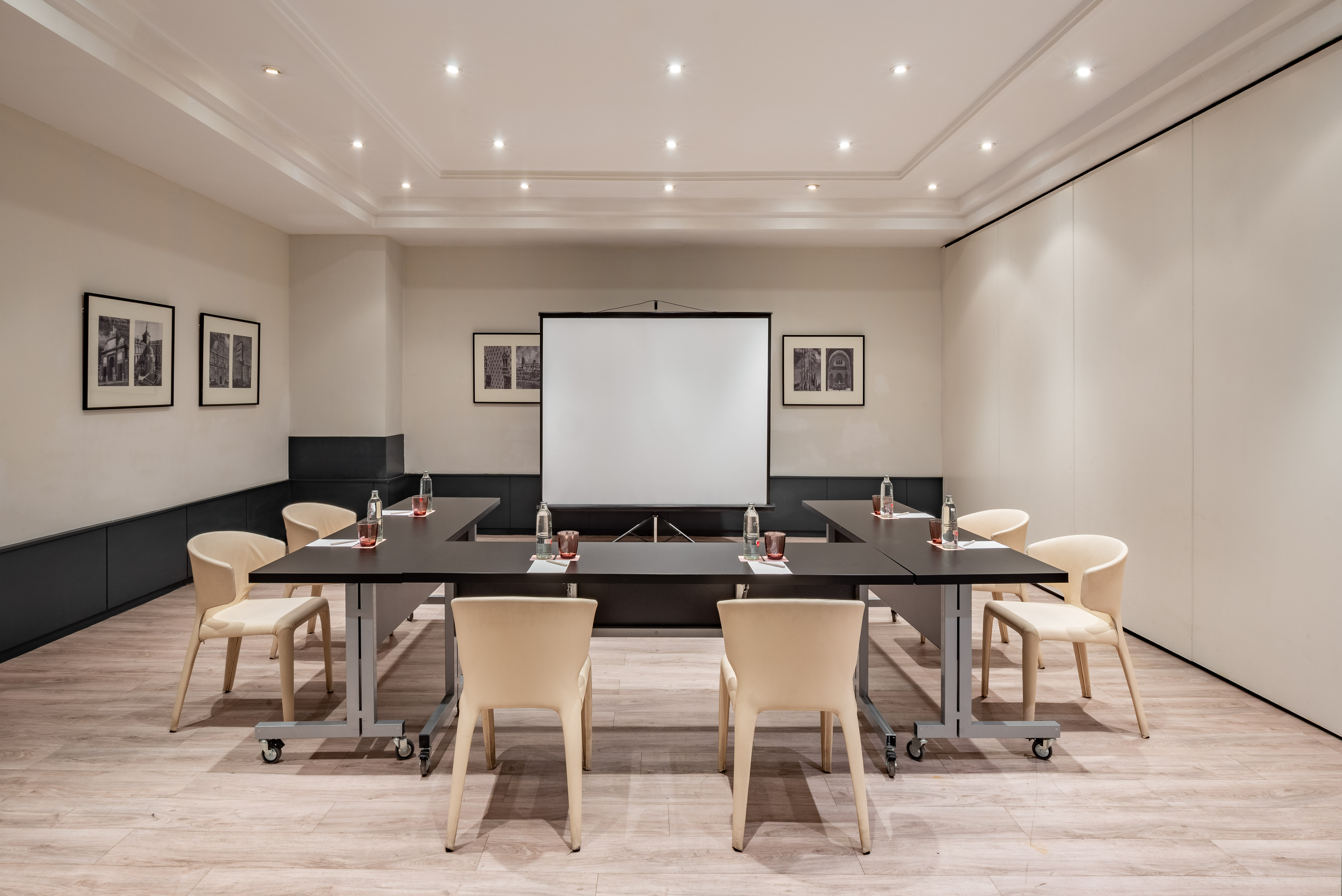 U-shape conference room with projector, dark tables, and light chairs.