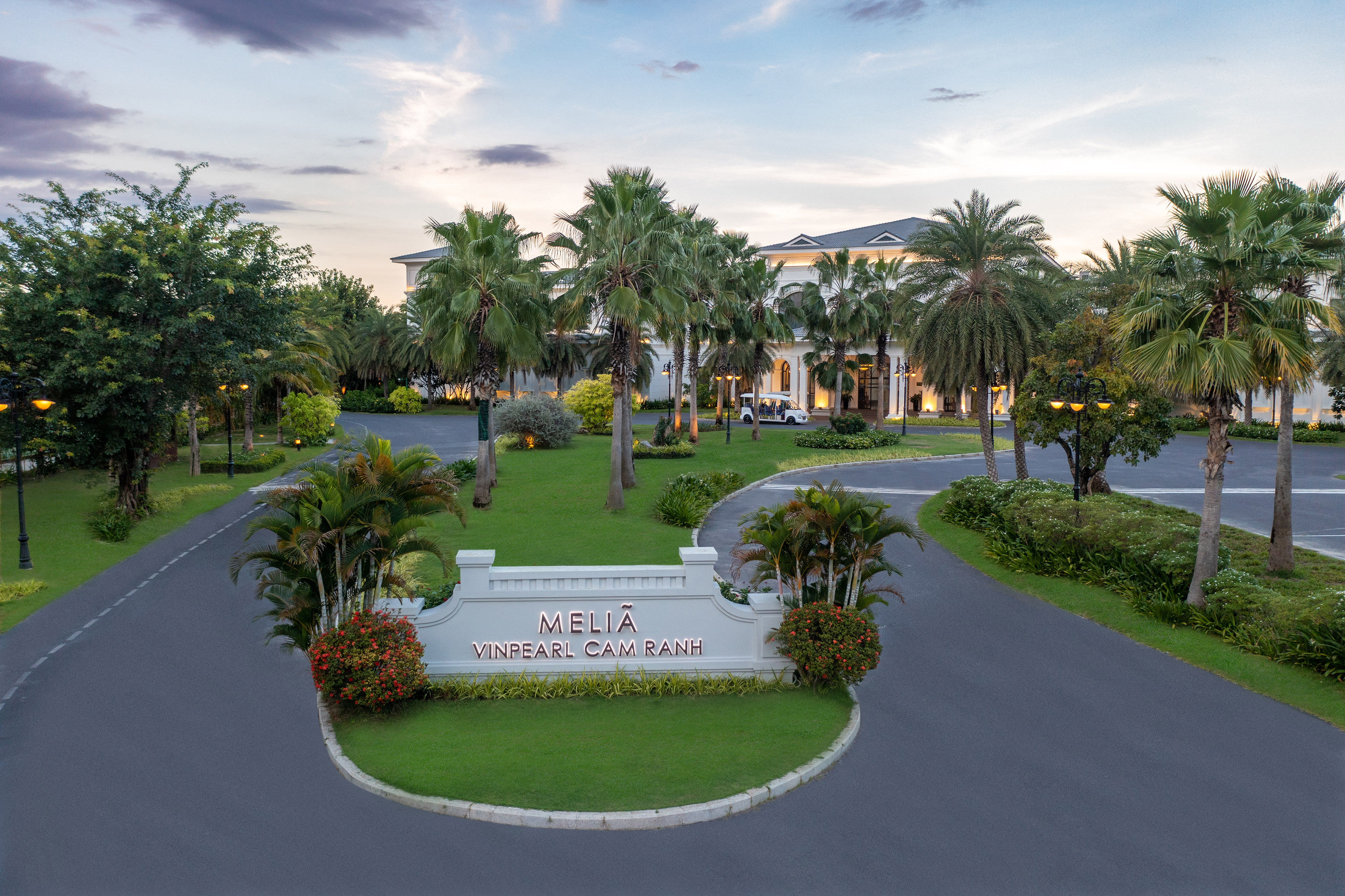Meliã Vinpearl Cam Ranh hotel entrance, palm trees, green landscaping at dusk.
