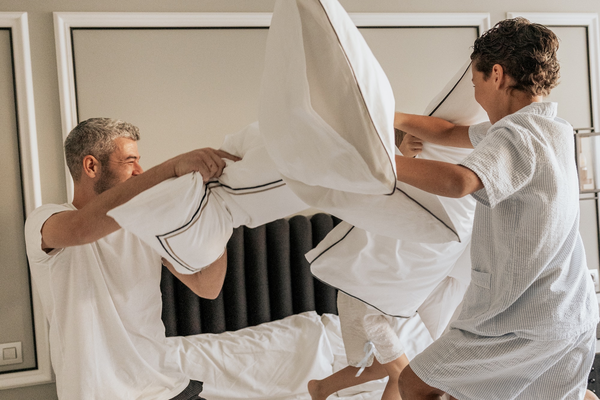 a group of people fighting pillows on a bed