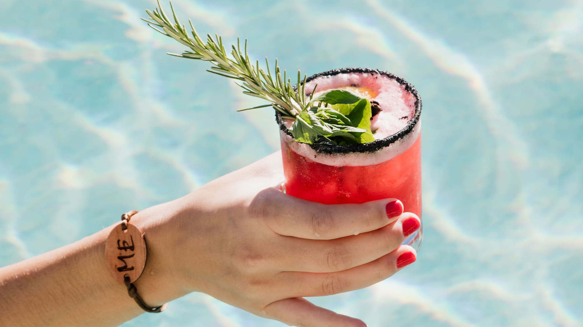 a hand holding a drink in a pool
